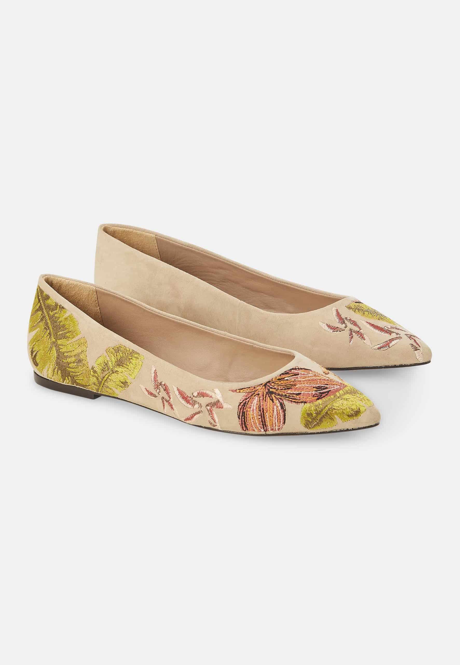 Pair of beige flats with floral embroidery on a white background