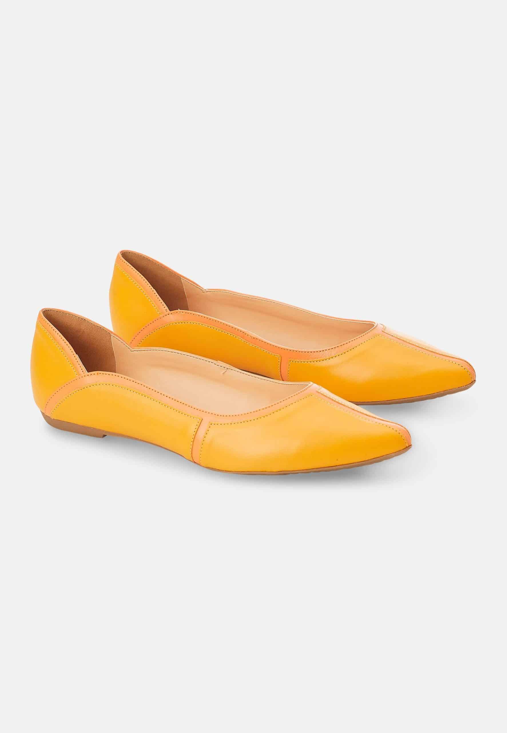 Pair of yellow pointed-toe flats on a light gray background