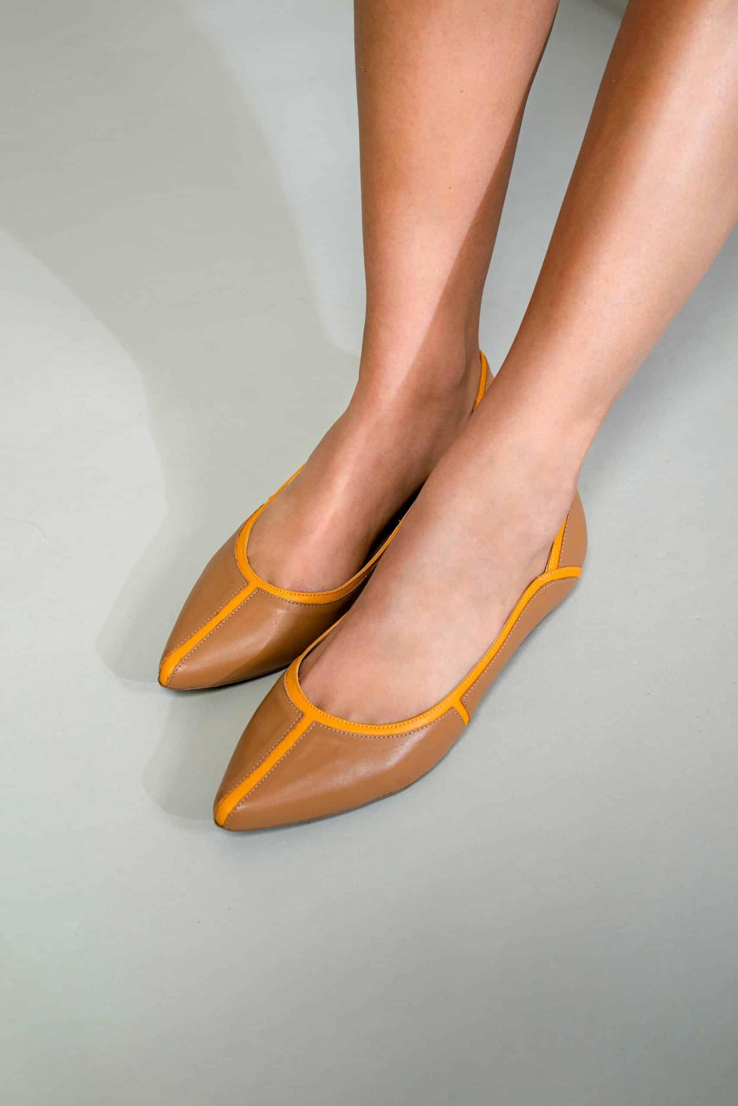 Brown shoes with yellow accents on a neutral background