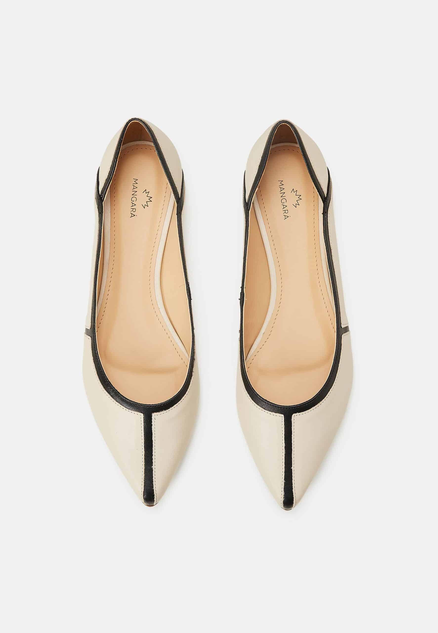 Pair of white pointed-toe shoes with black accents on a light gray background