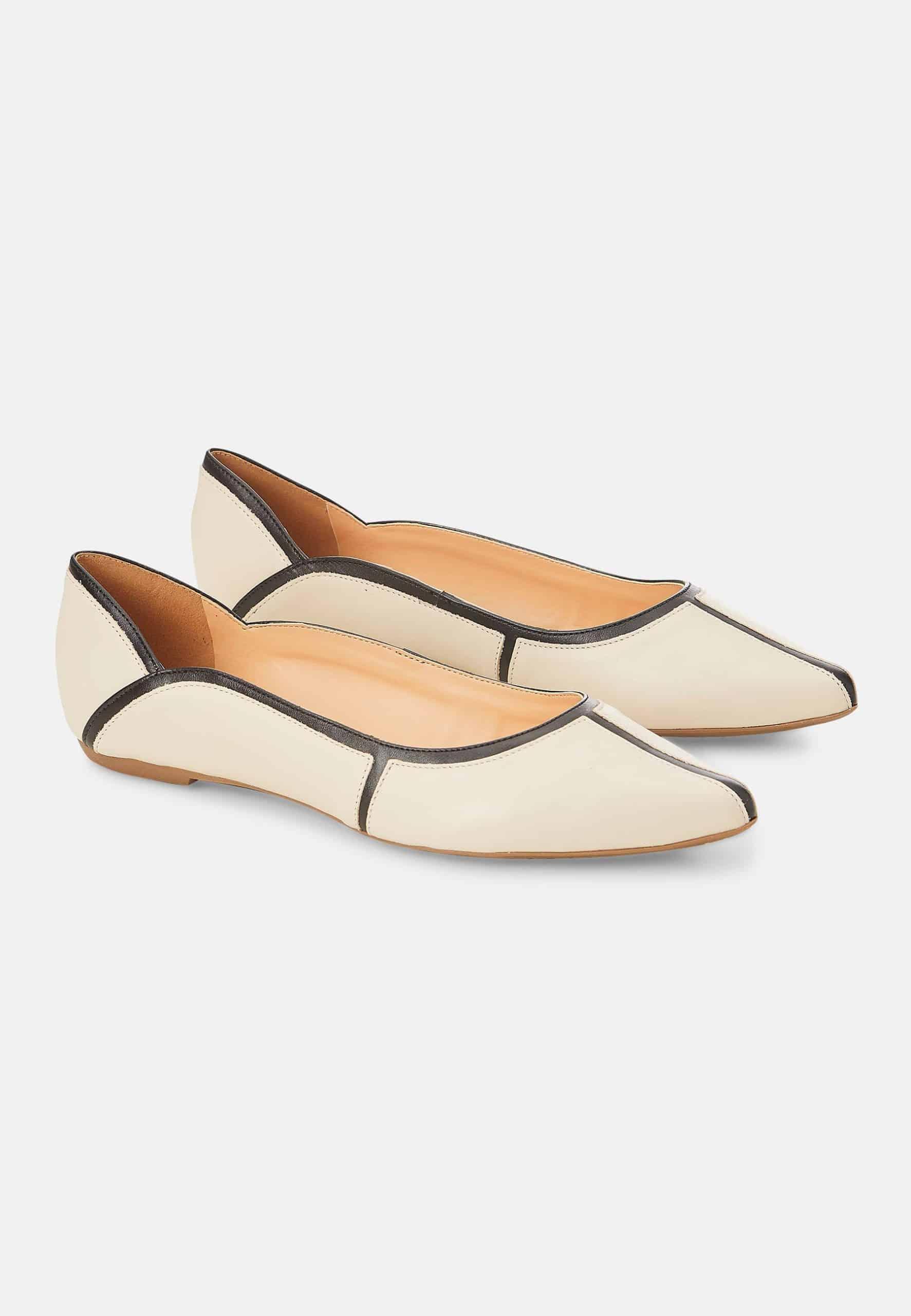 Pair of cream-colored flats with brown accents on a light gray background