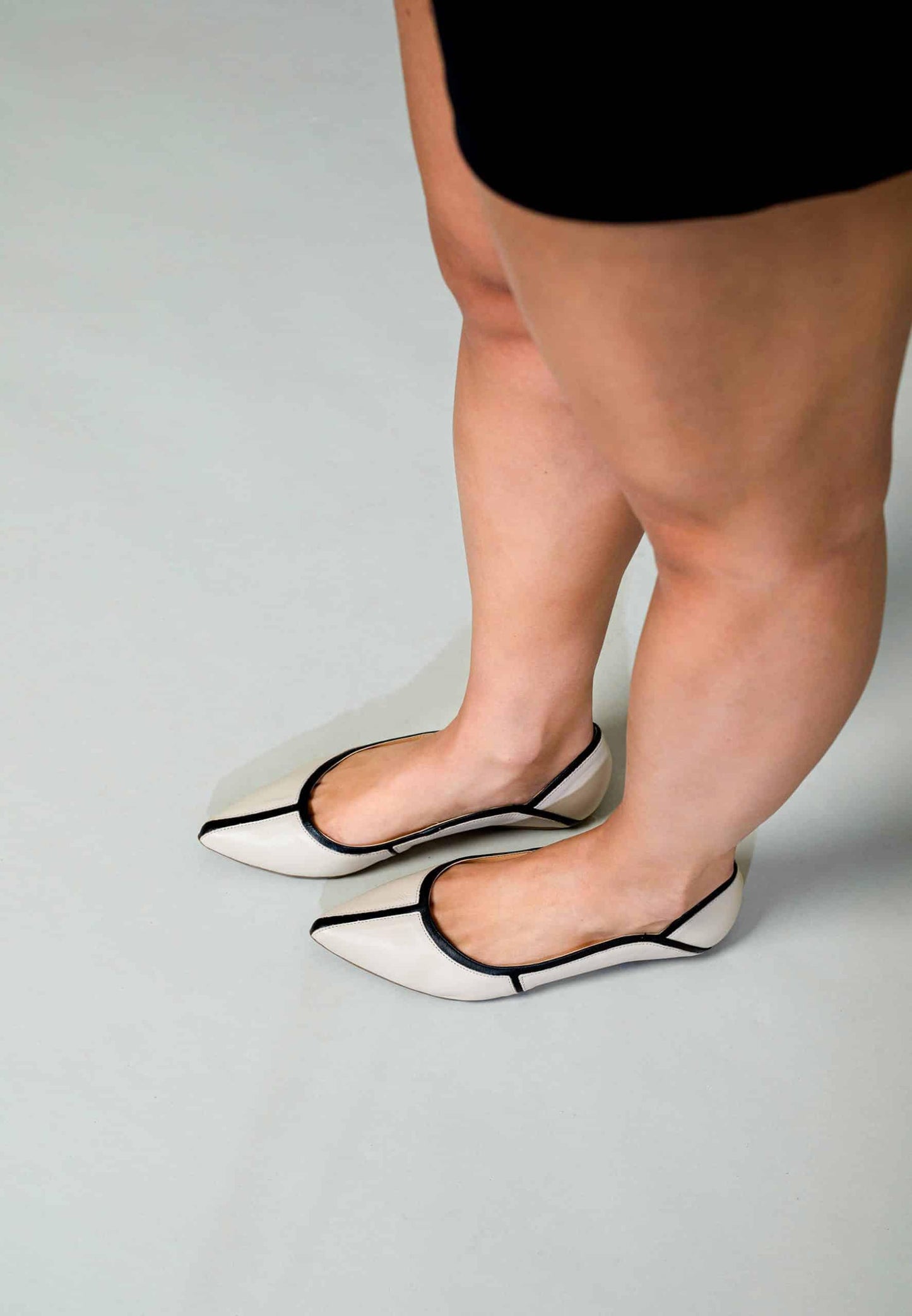 White shoes with black accents worn by a person on a light gray background