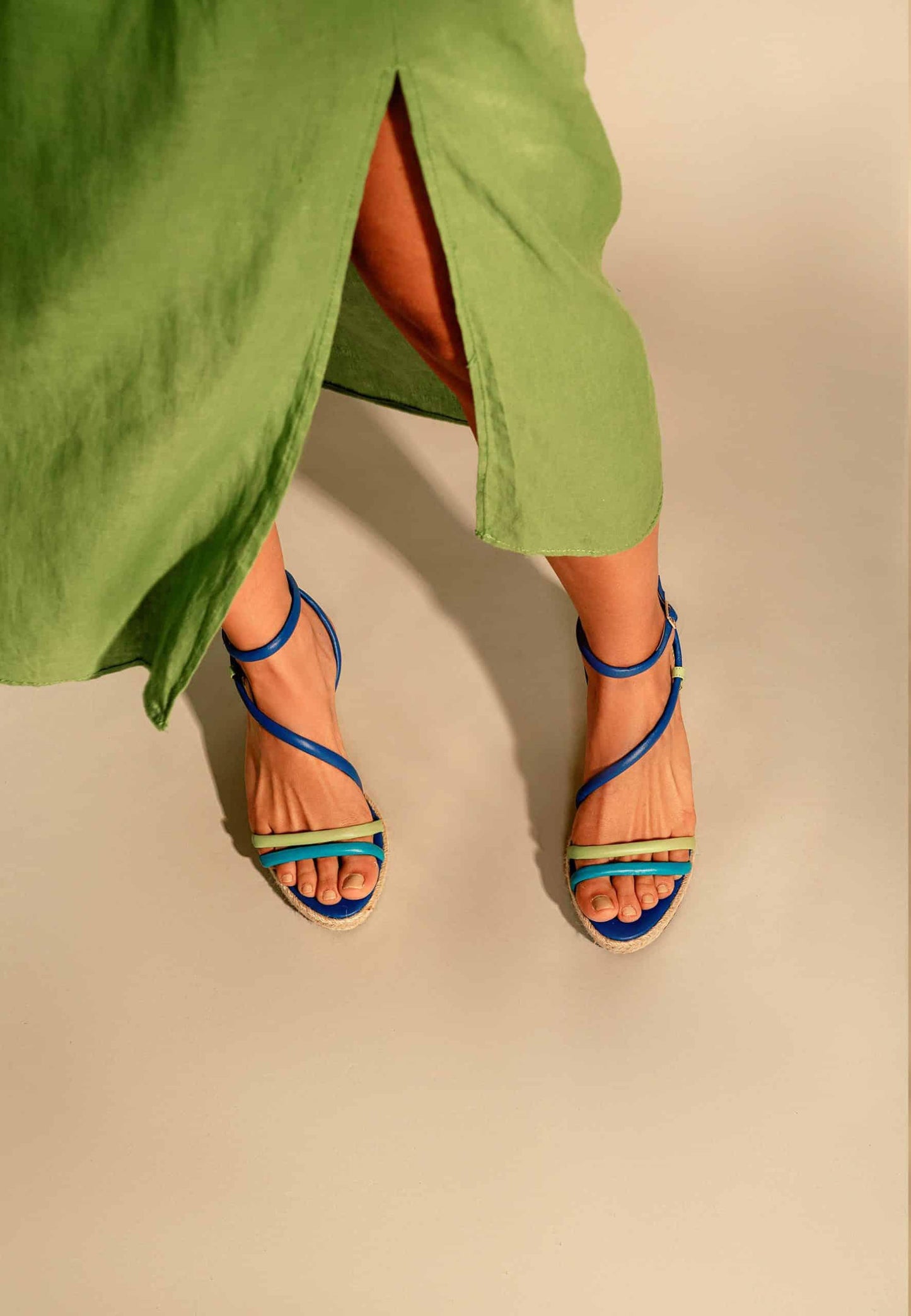 Person wearing green pants and blue sandals on a beige background