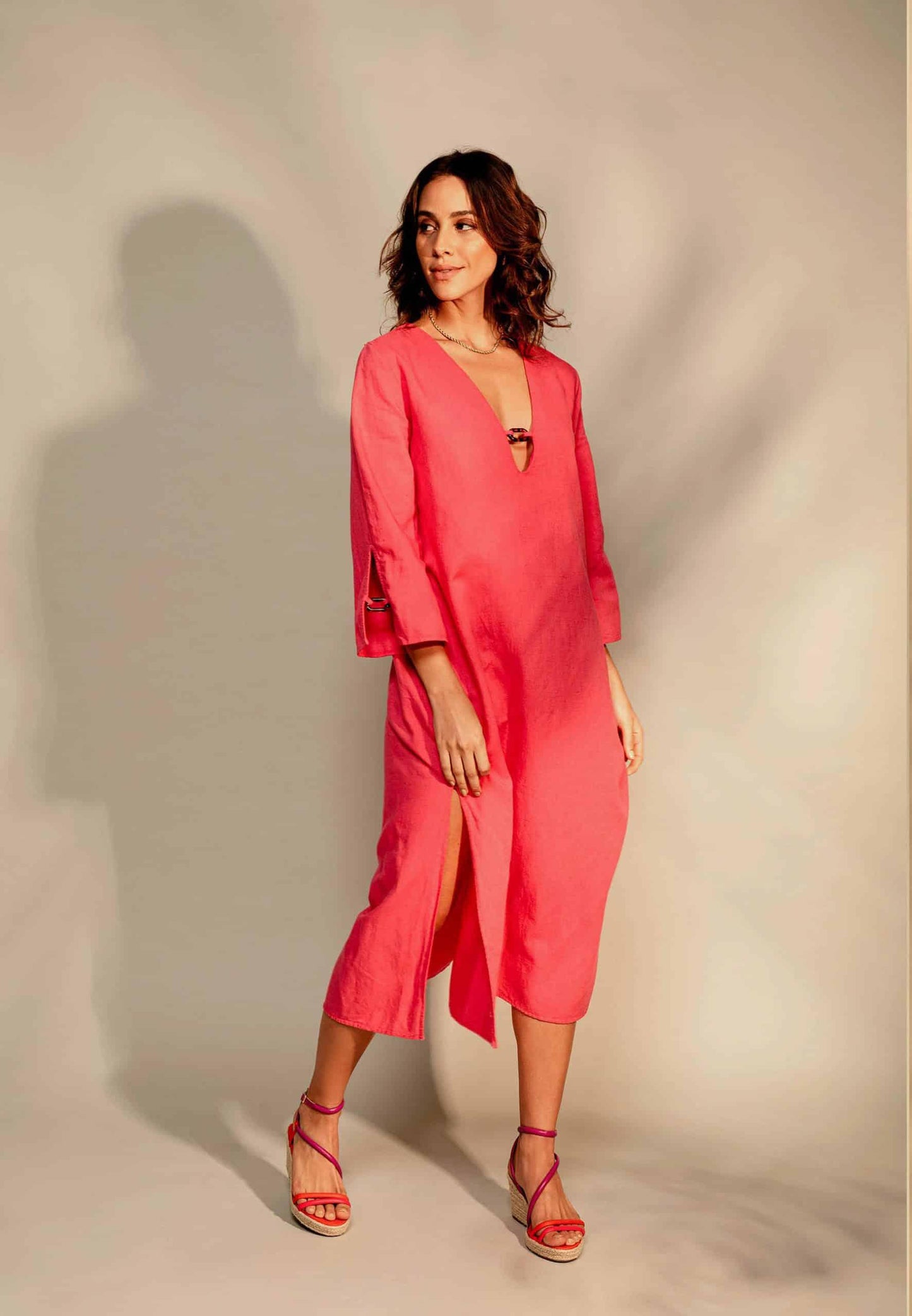 Woman wearing a coral pink dress with a plain background