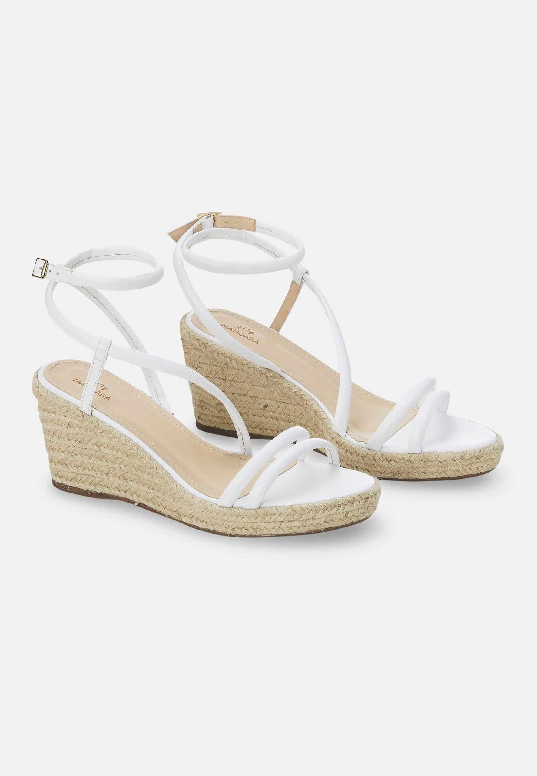 White wedge sandals with espadrille sole on a light gray background
