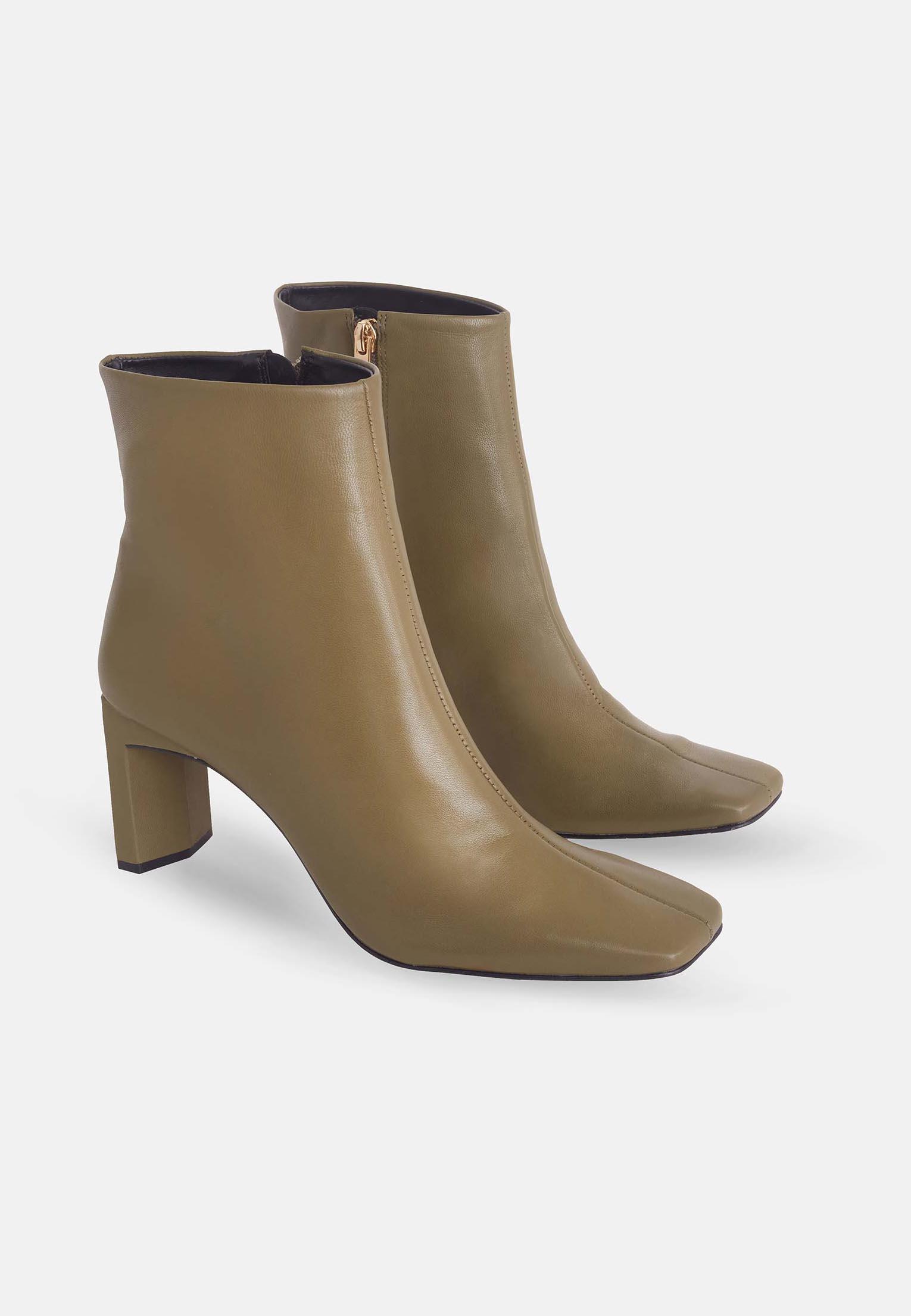 Pair of olive green ankle boots on a white background