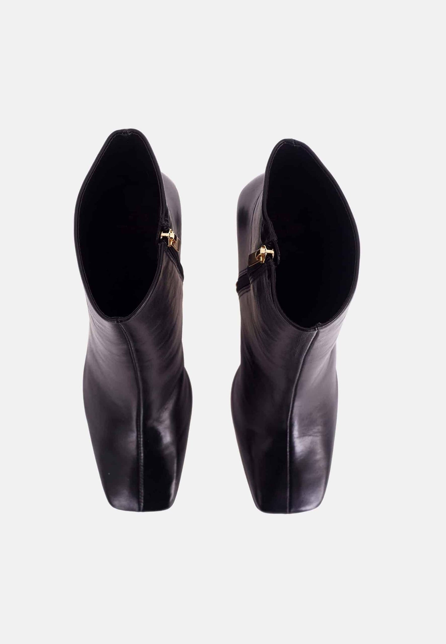 Pair of black leather ankle boots with gold buckles on a white background