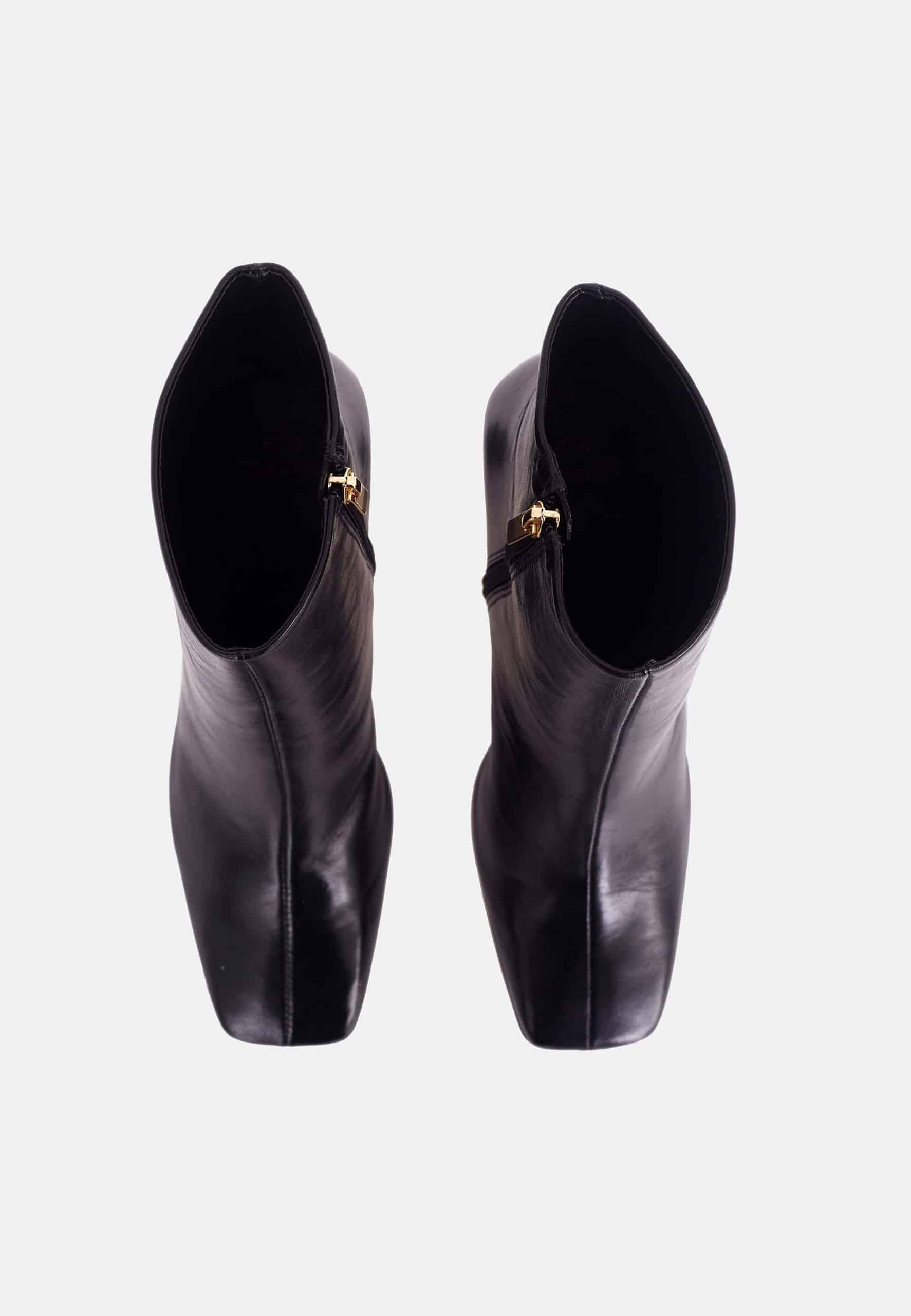 Pair of black leather ankle boots with gold buckles on a white background