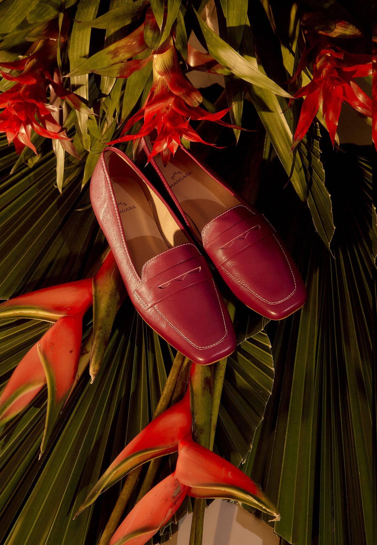 Red loafers on a background of tropical plants with red flowers