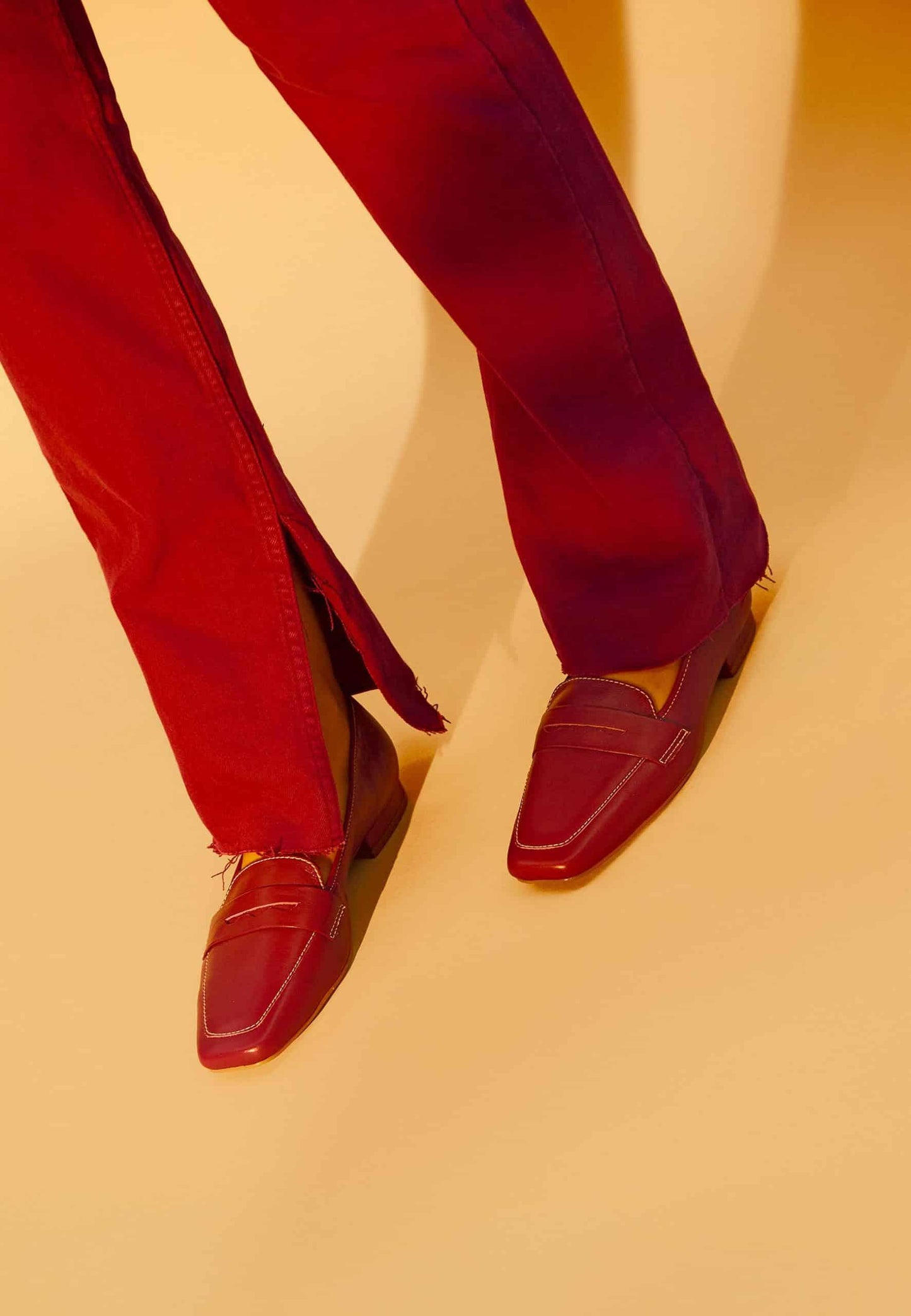 Red loafers and pants on a beige background