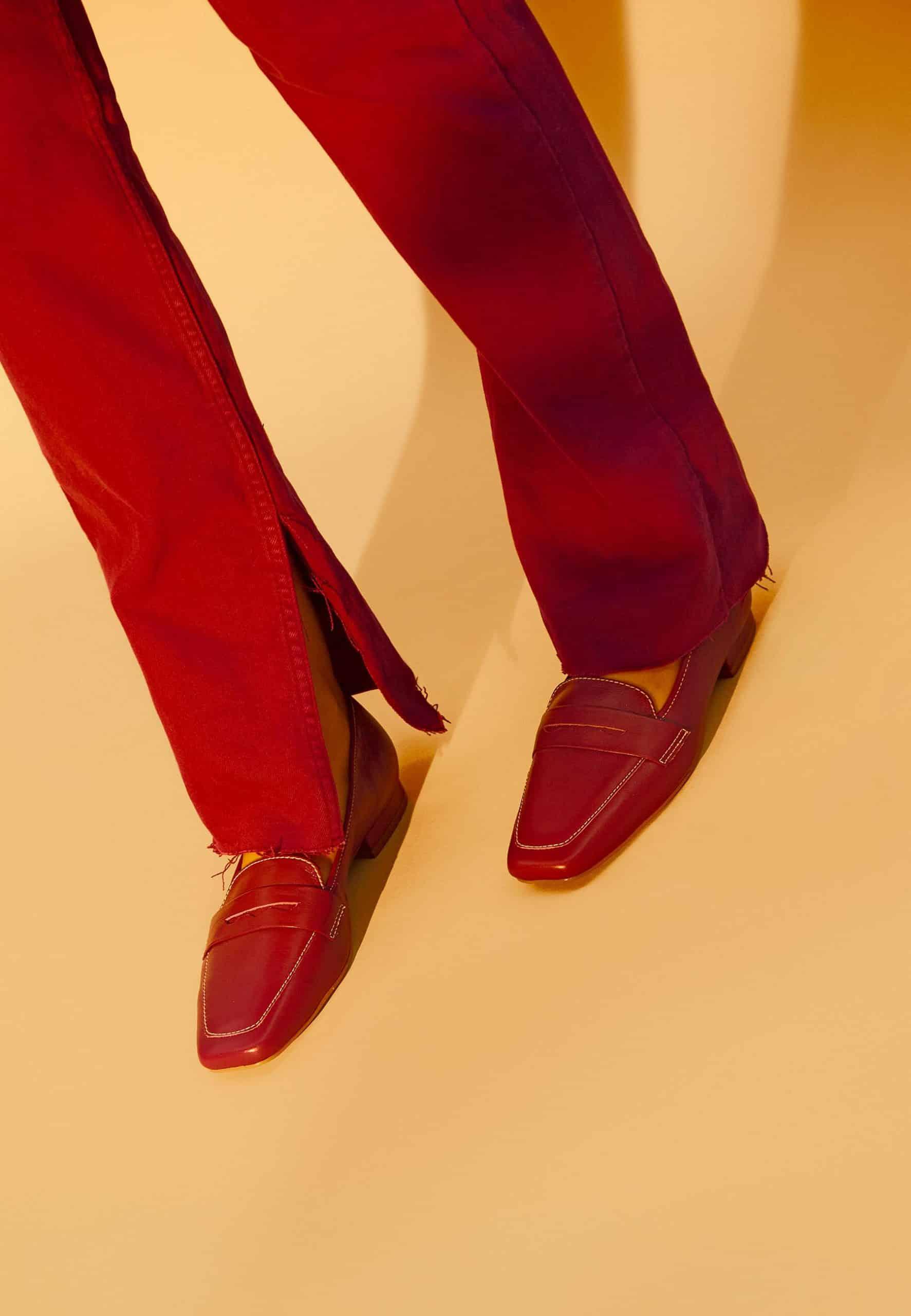 Red loafers and pants on a beige background