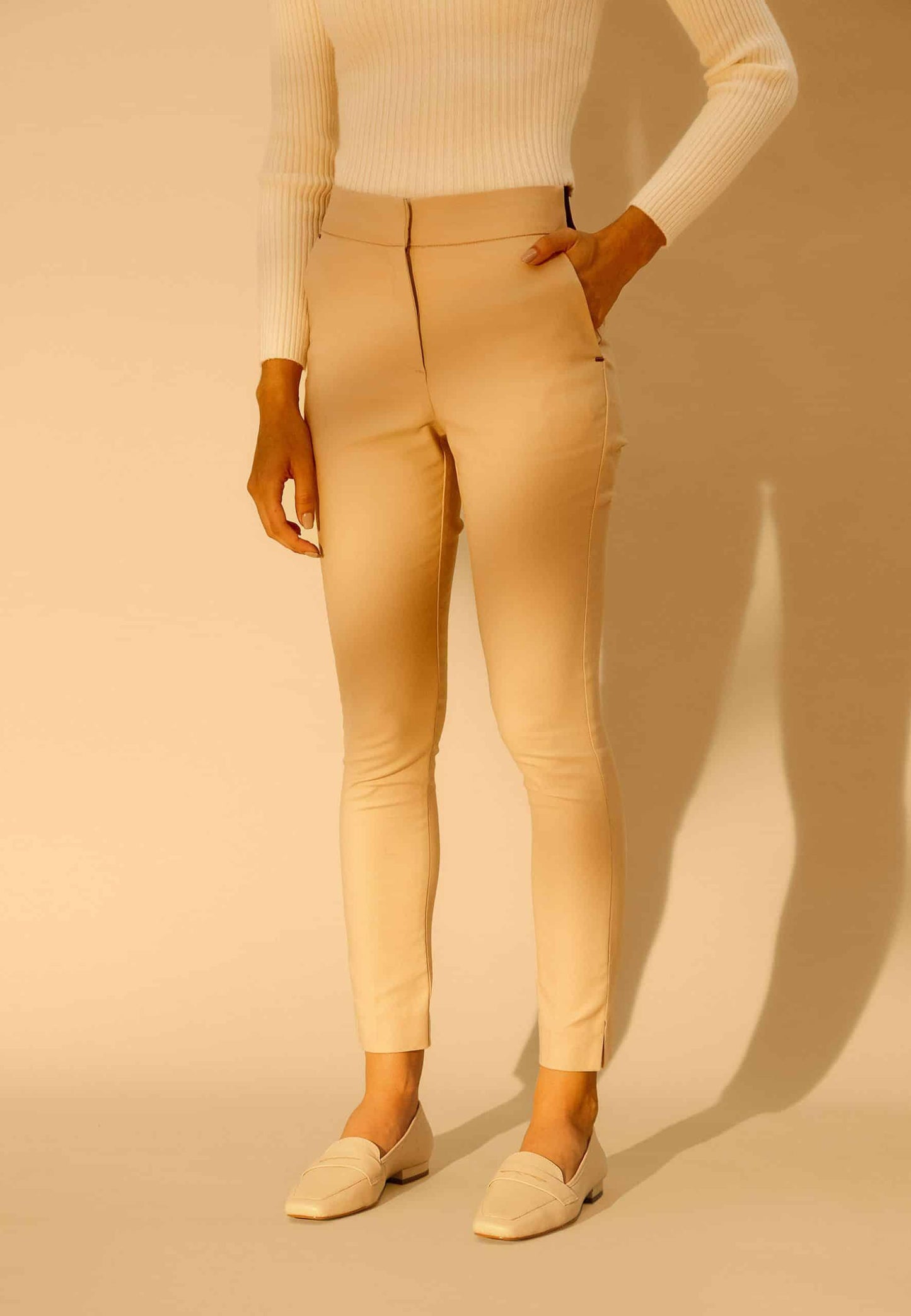 Person wearing beige pants and a cream sweater on a beige background