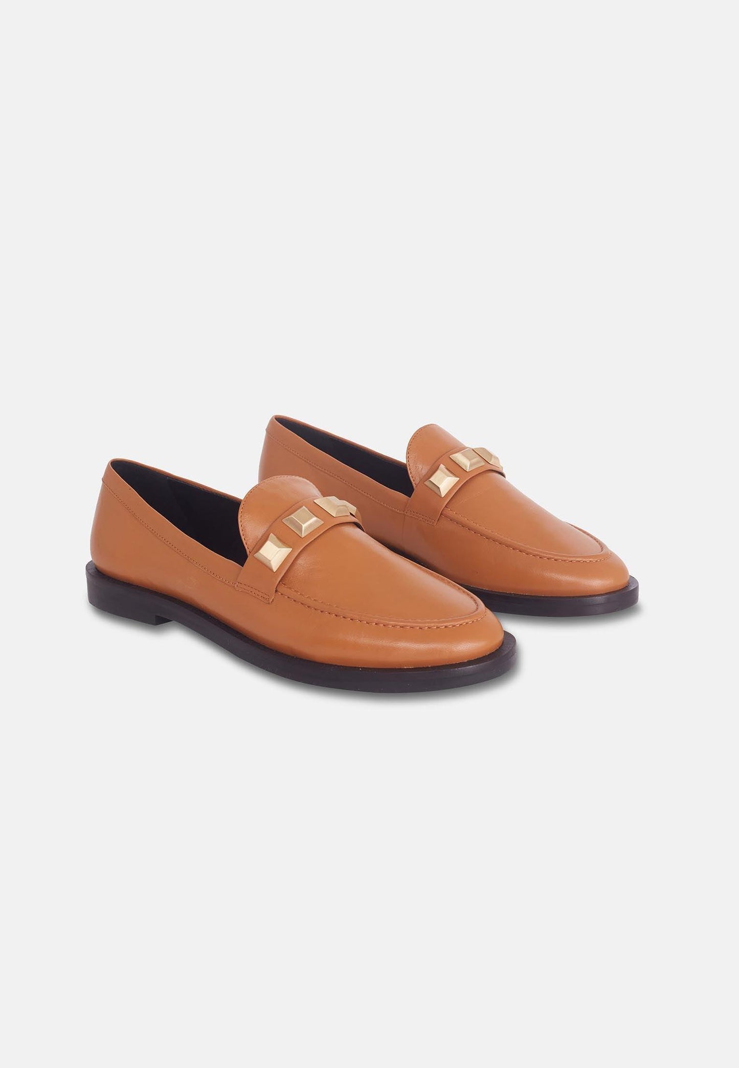 Pair of tan loafers with gold accents on a white background