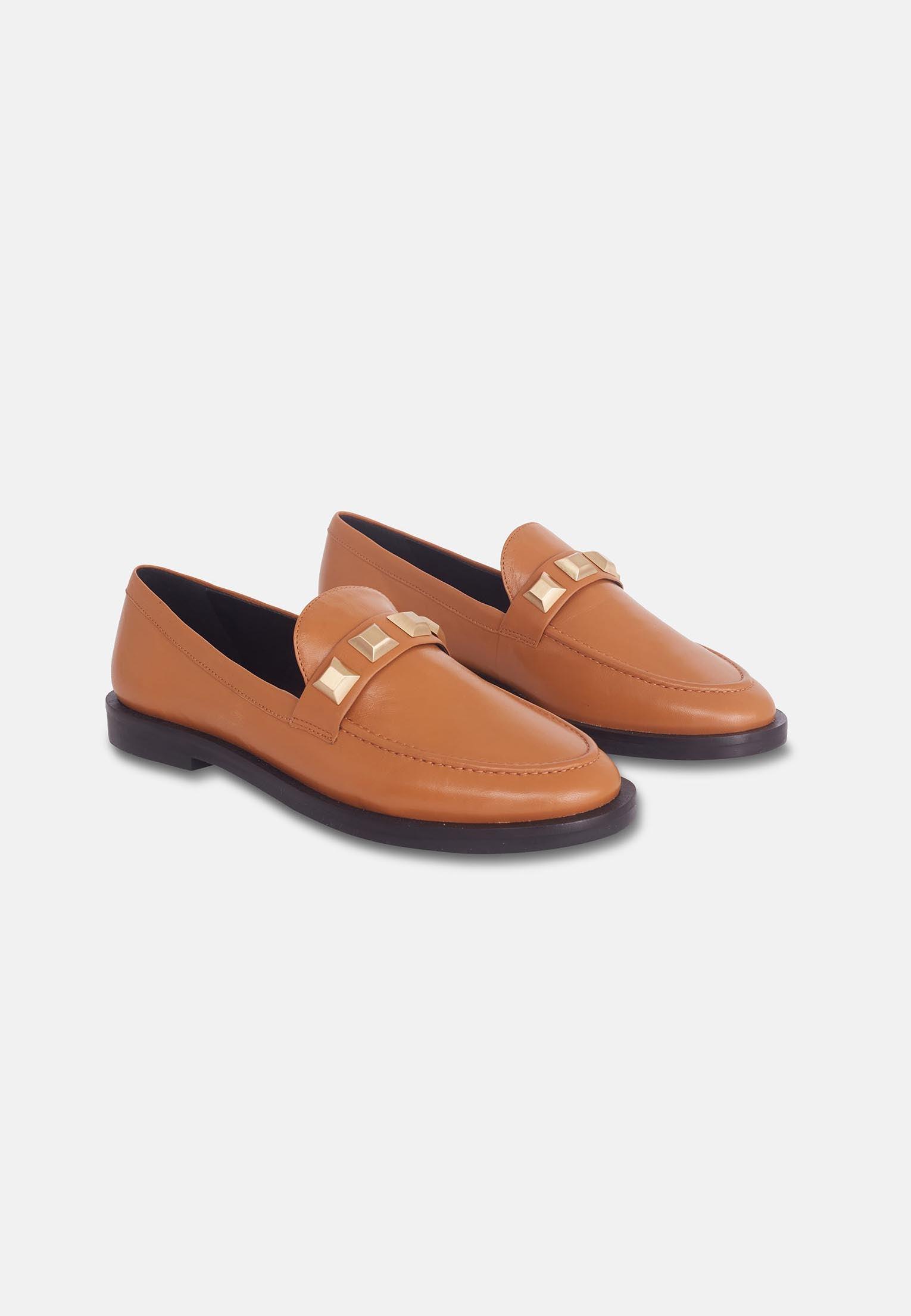 Pair of tan loafers with gold accents on a white background