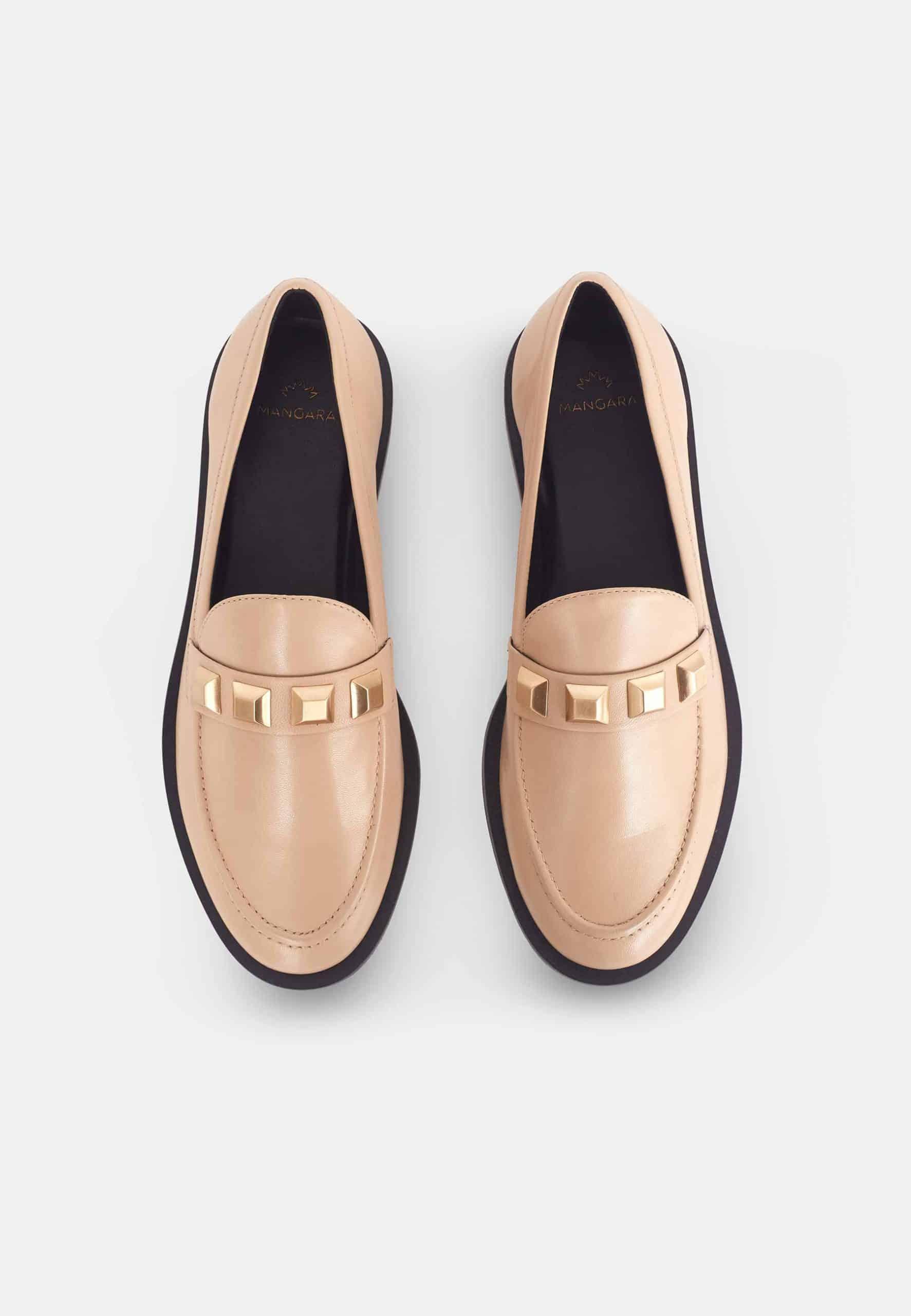 Pair of beige loafers with gold accents on a light gray background