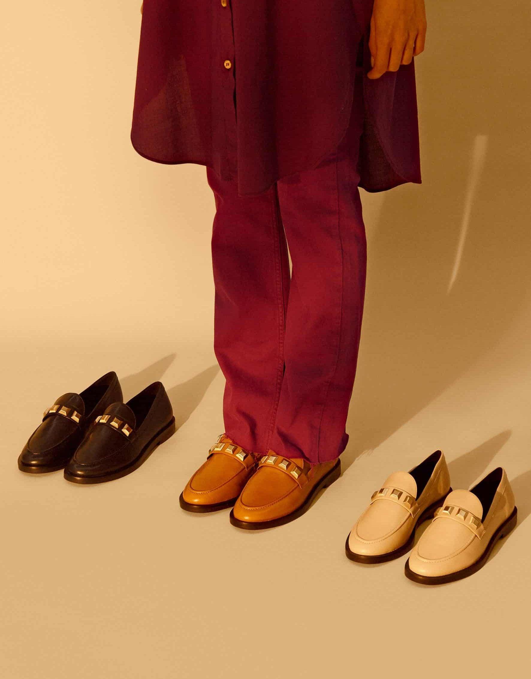 Person wearing a burgundy outfit with loafers on a beige background