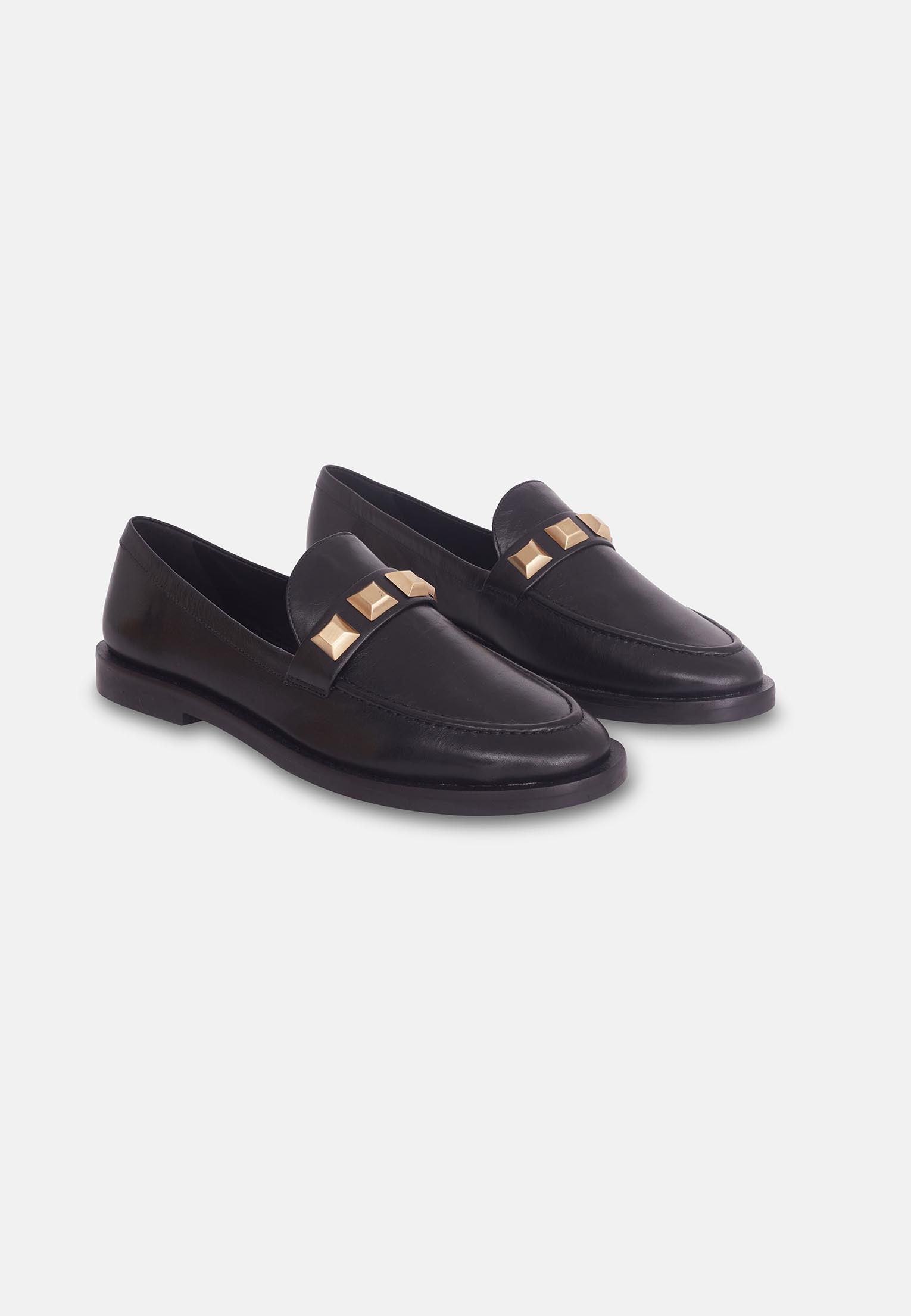 Black loafers with gold accents on a white background