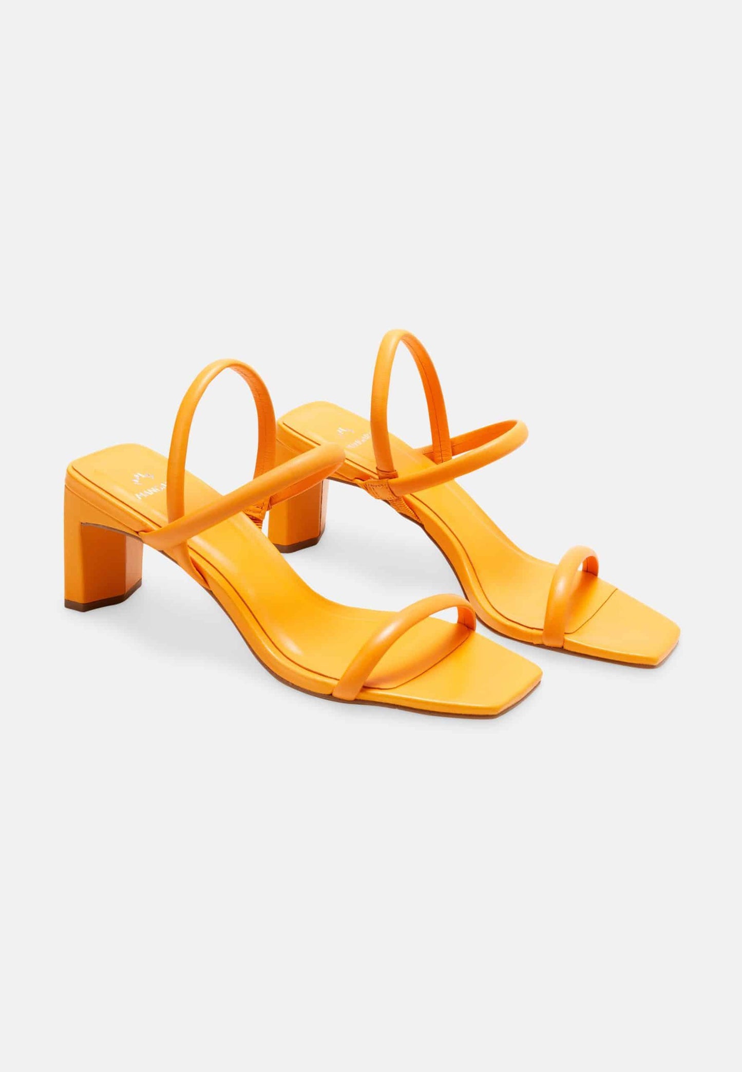 Pair of orange high-heeled sandals on a light gray background