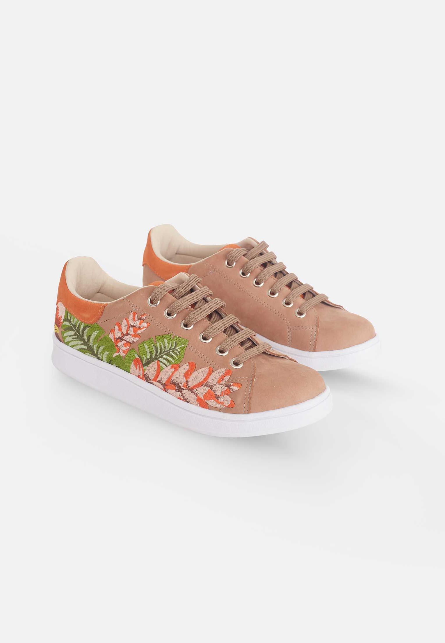 Pair of tan sneakers with floral designs on a white background