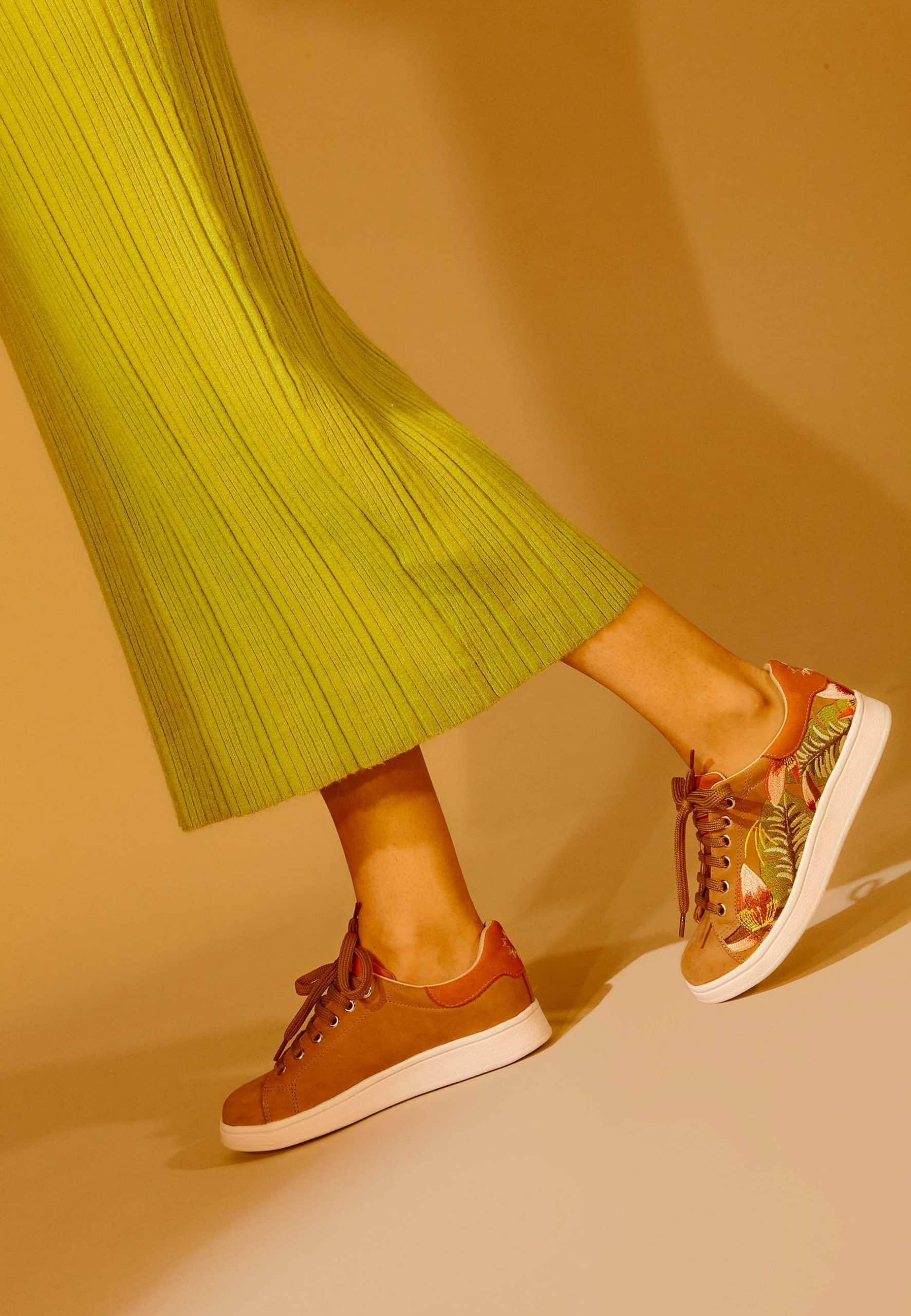 Person wearing brown sneakers with floral pattern on a beige background
