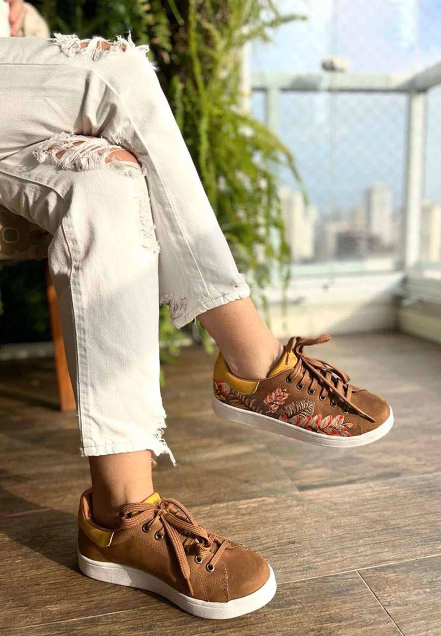 Person wearing brown sneakers with floral patterns indoors.