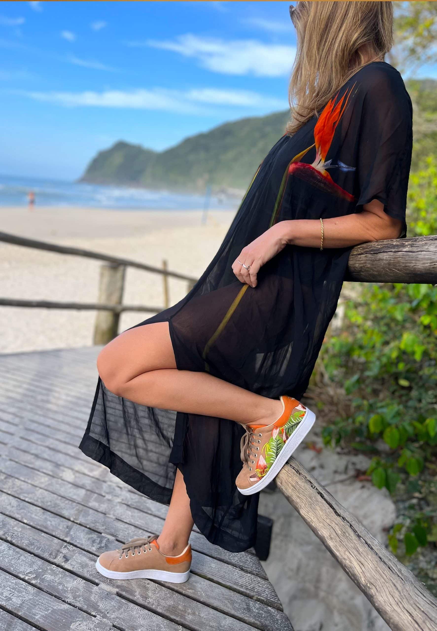 Woman sitting on a wooden bench by a beach with a scenic view.
