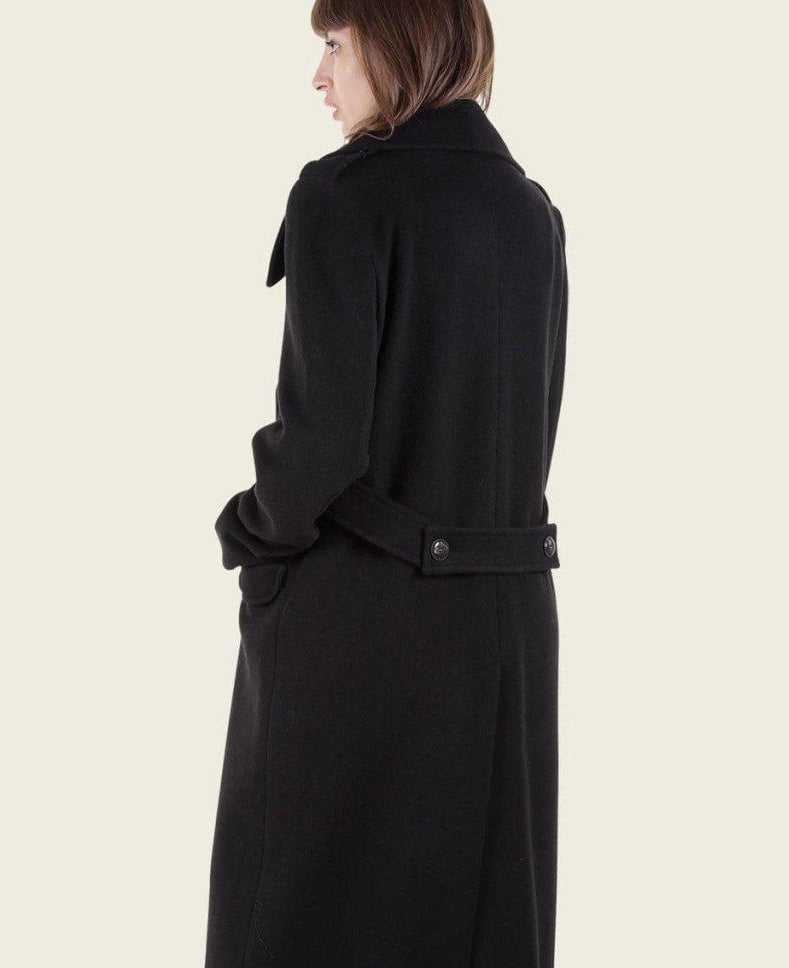 Person wearing a black coat on a plain background