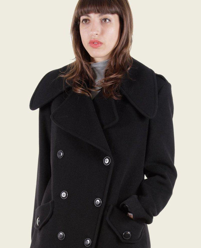 Woman wearing a black coat with a collar on a plain background