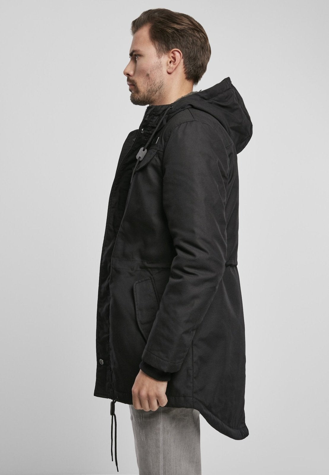 Man wearing a black hooded coat on a light gray background