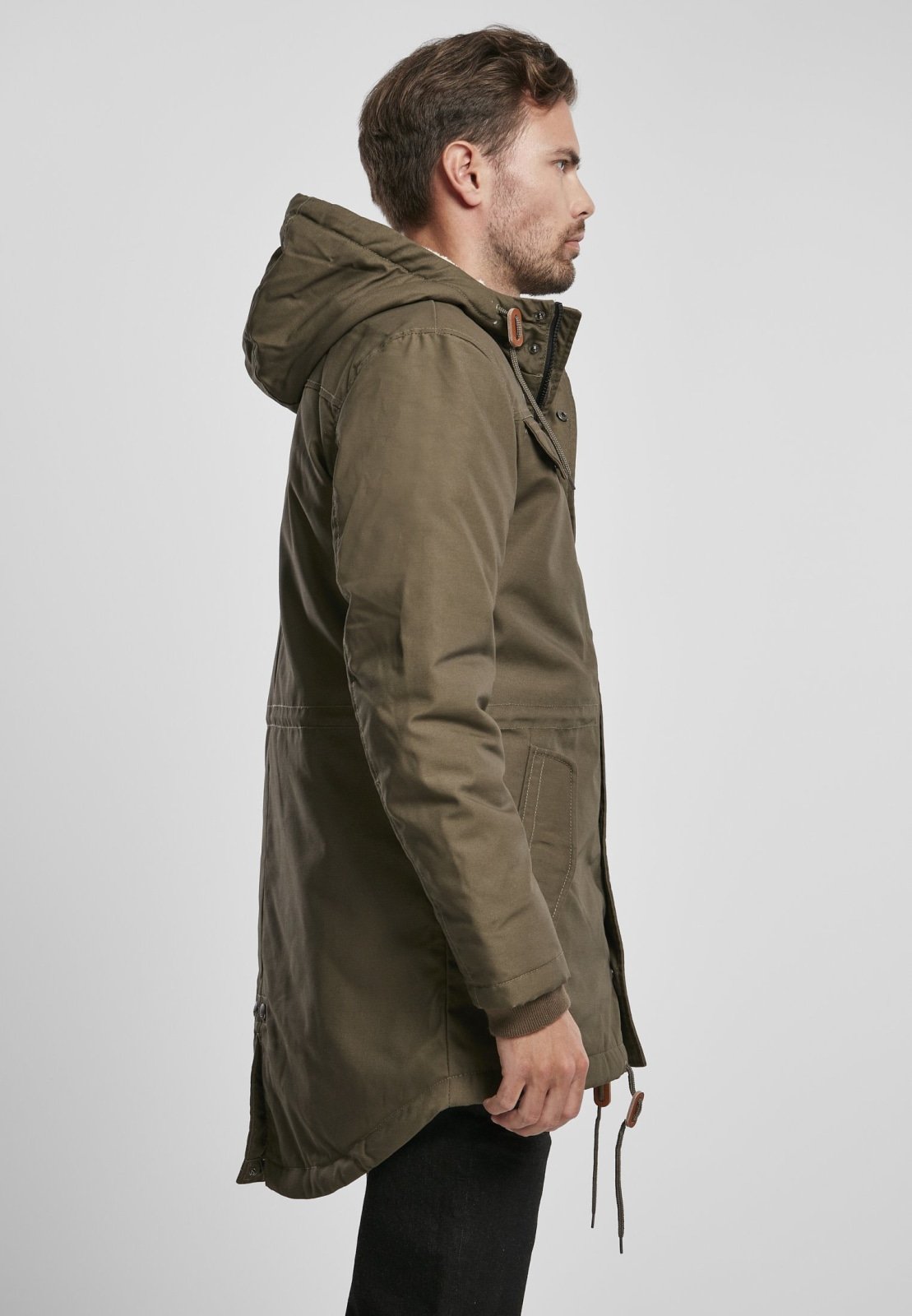 Man wearing a green hooded jacket on a light gray background