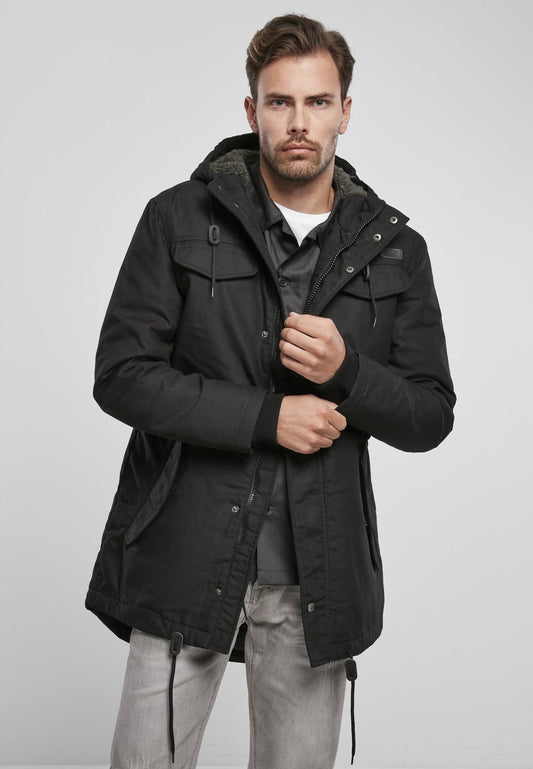 Man wearing a black parka jacket on a light gray background