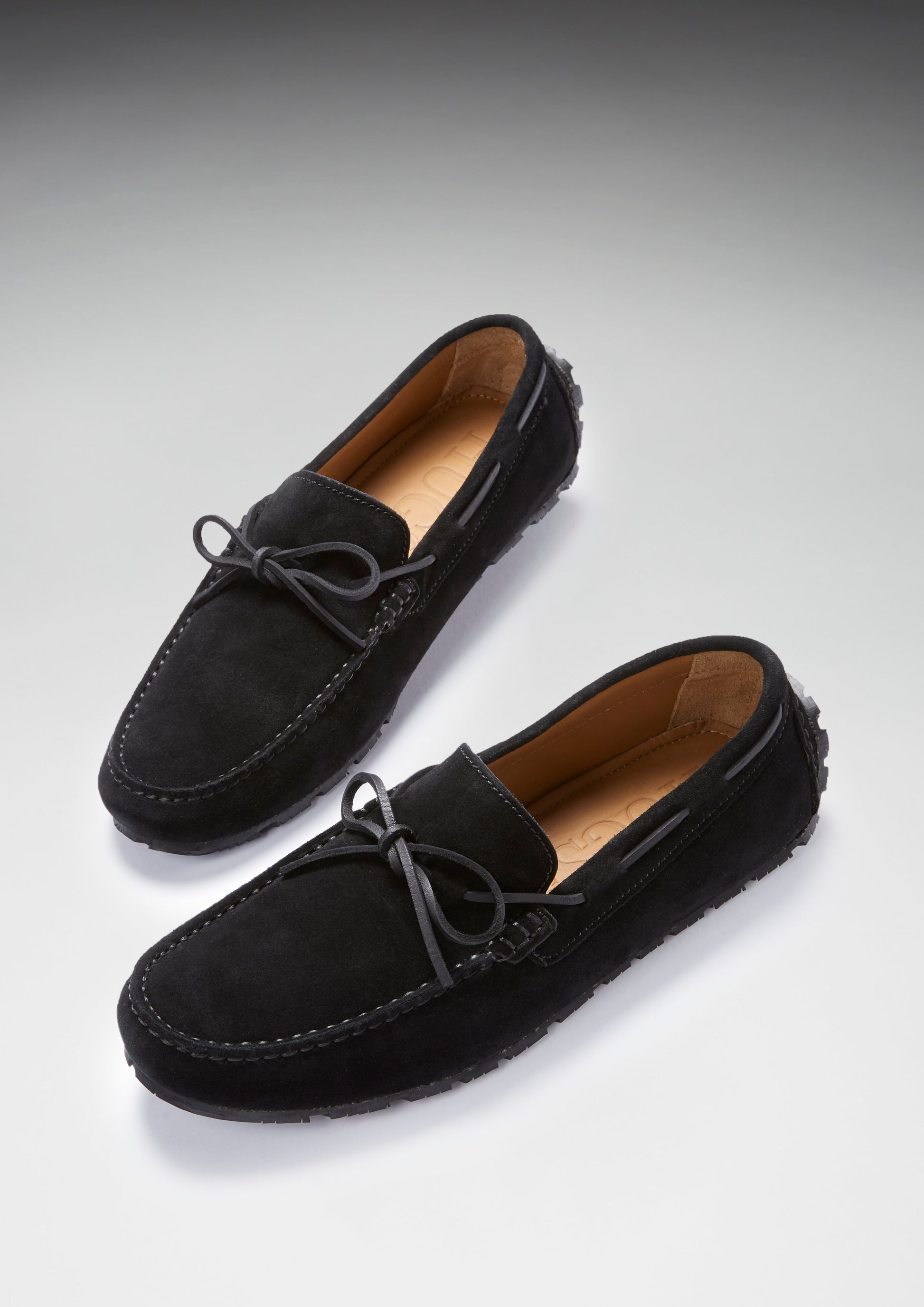 Pair of black suede loafers on a light gray background