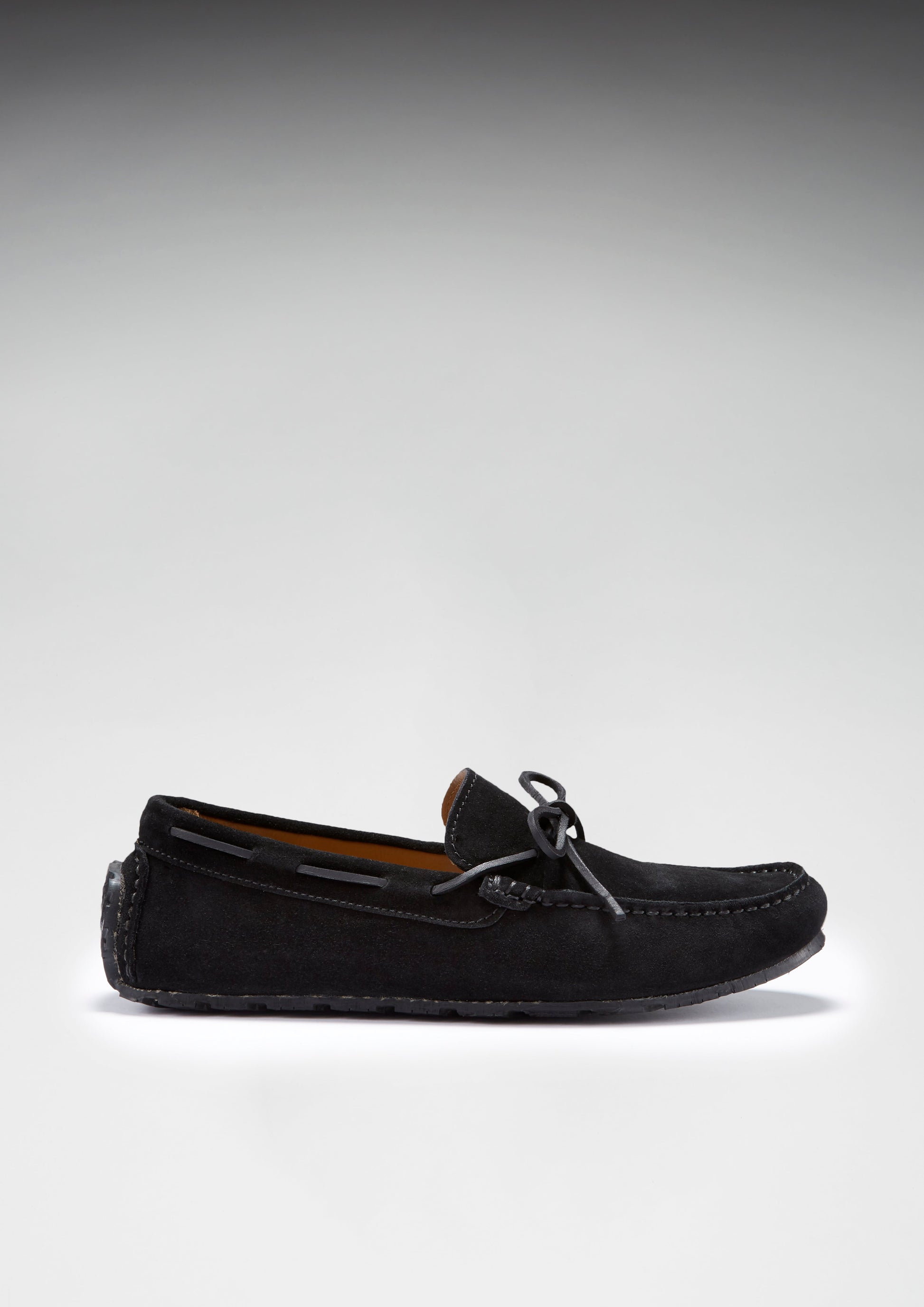 Black suede loafer shoe on a light gray background