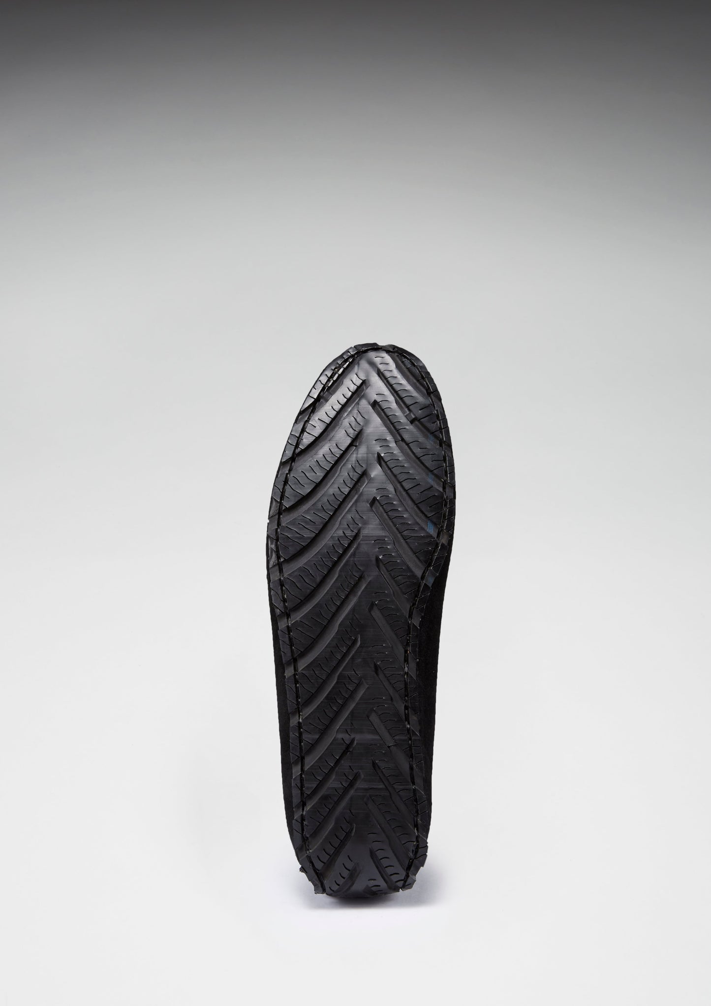 Black shoe sole with tread pattern on a gray background