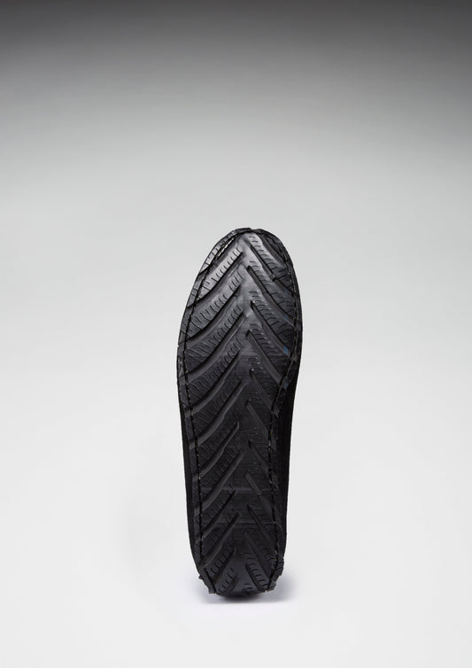 Black shoe sole with tread pattern on a gray background