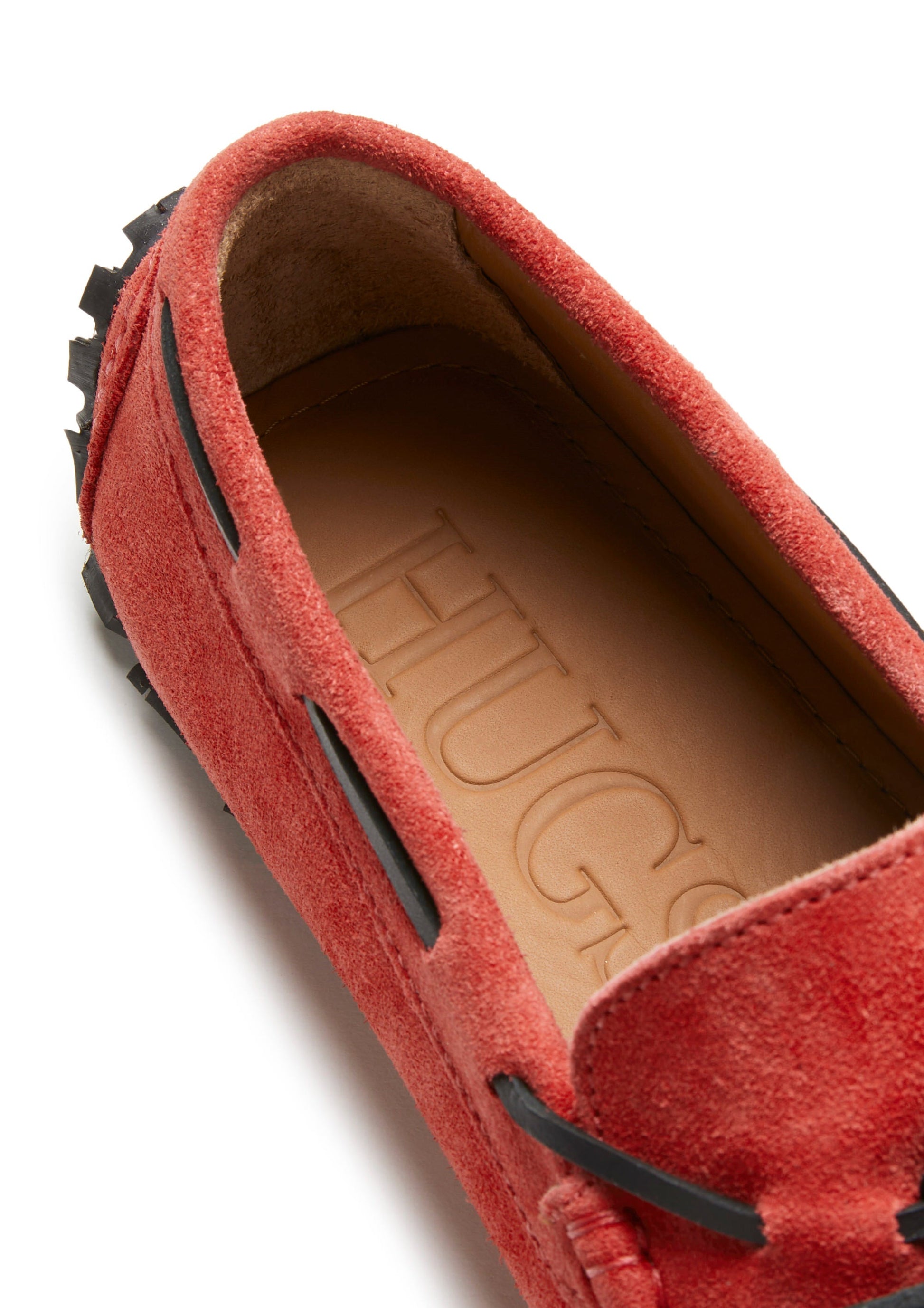 Red suede loafer with 'HUGS' branding on a white background