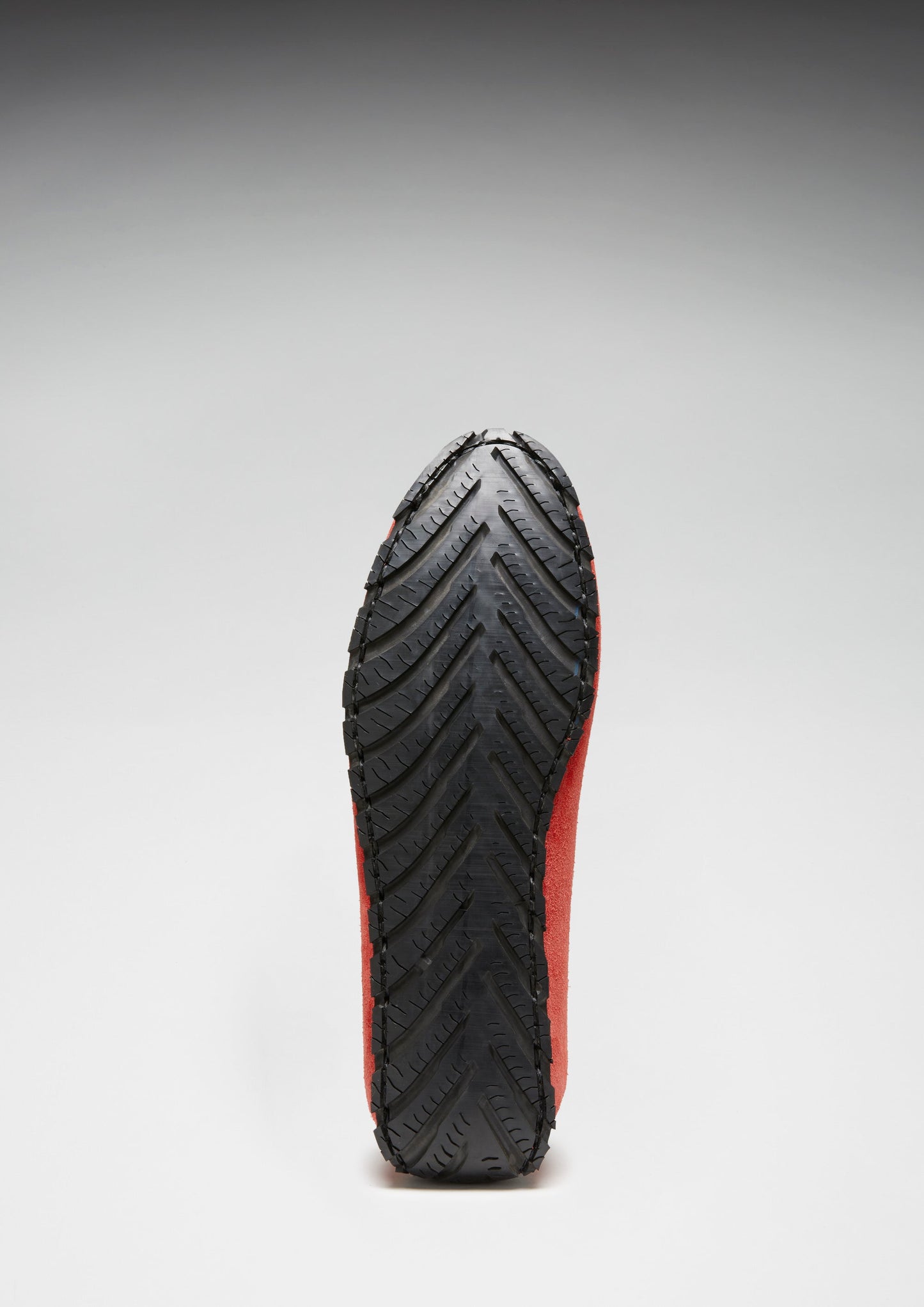 Black and red sole of a shoe on a gray background
