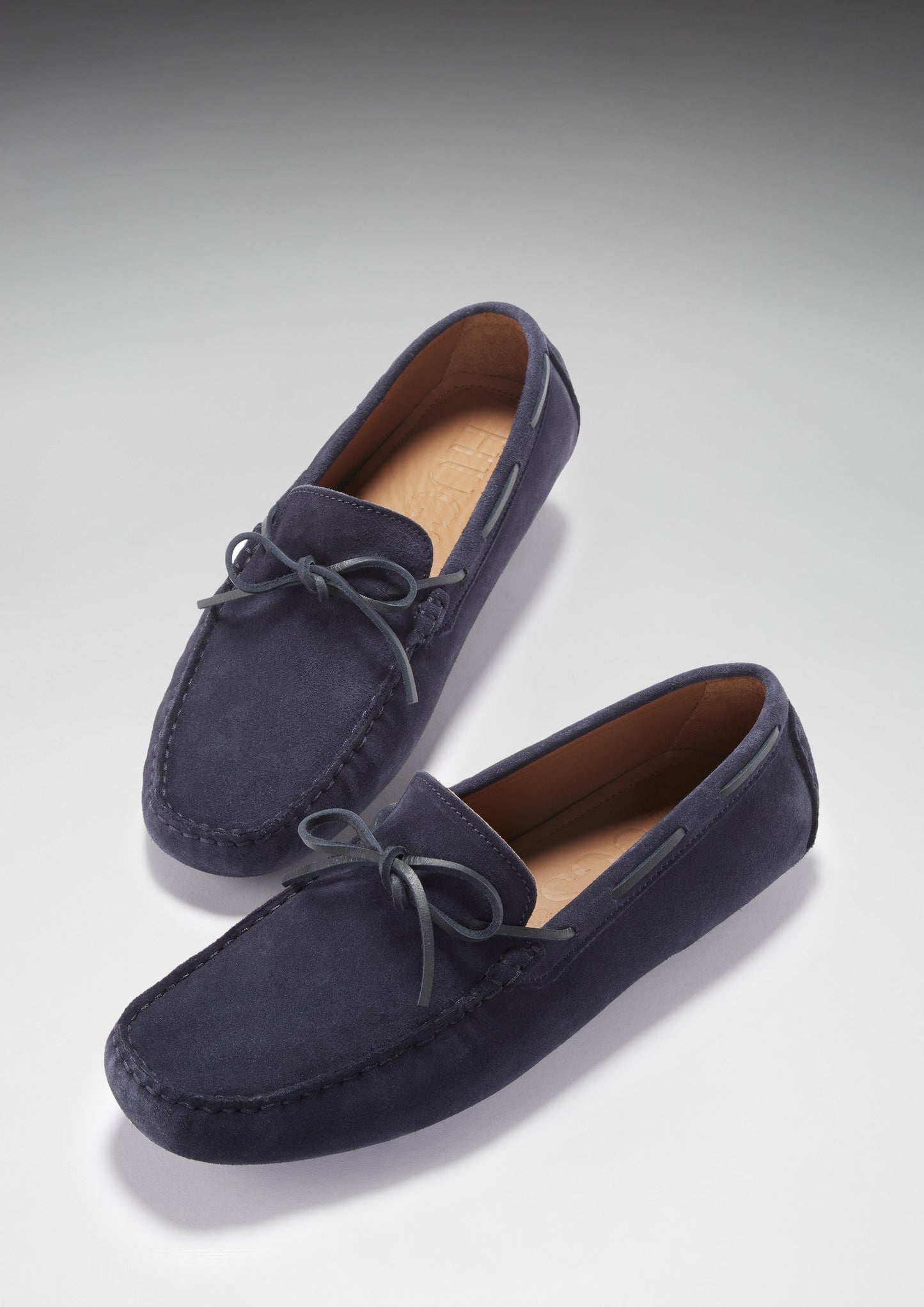 Navy blue suede loafers on a light gray background