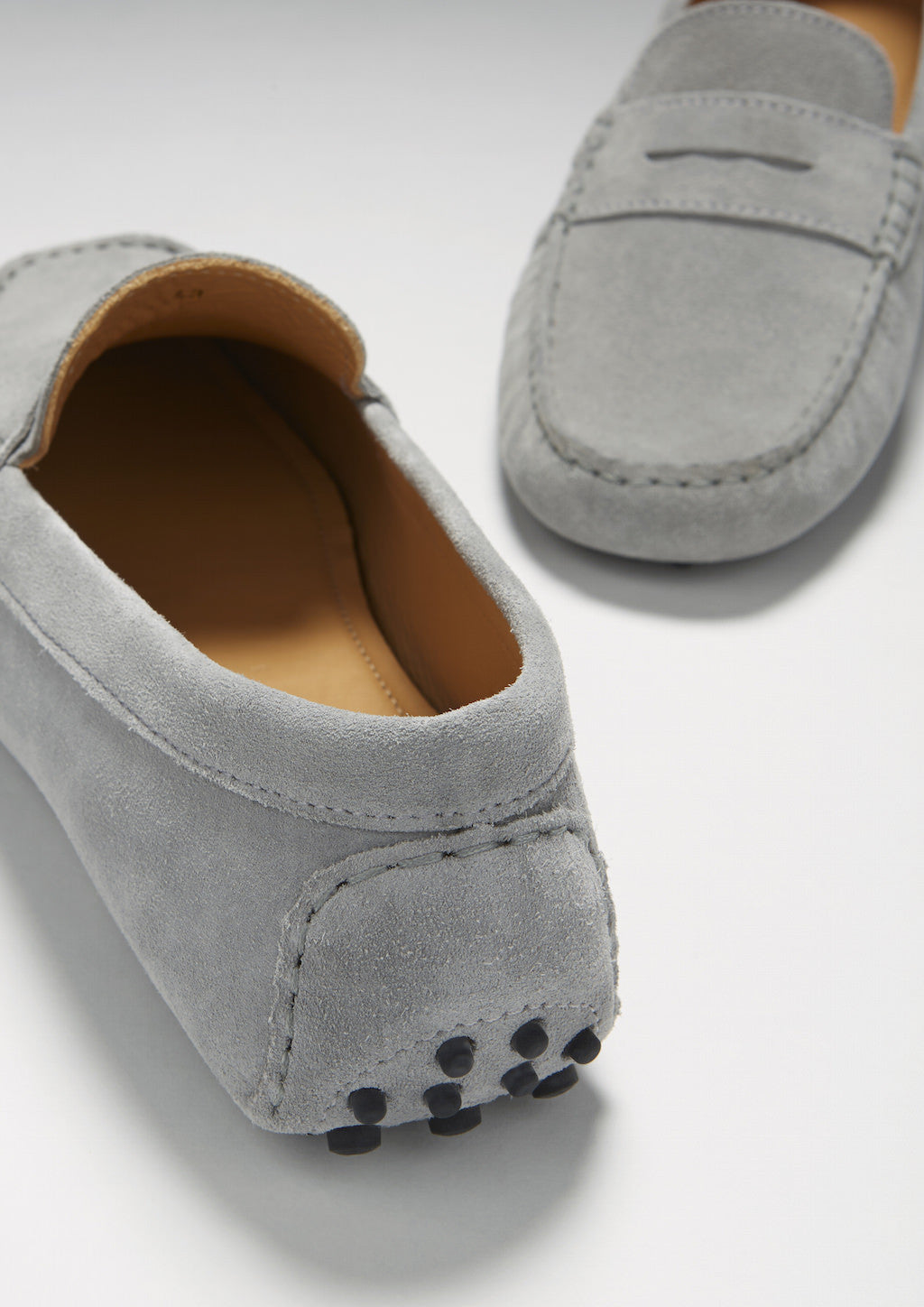 Gray suede loafers on a light gray background