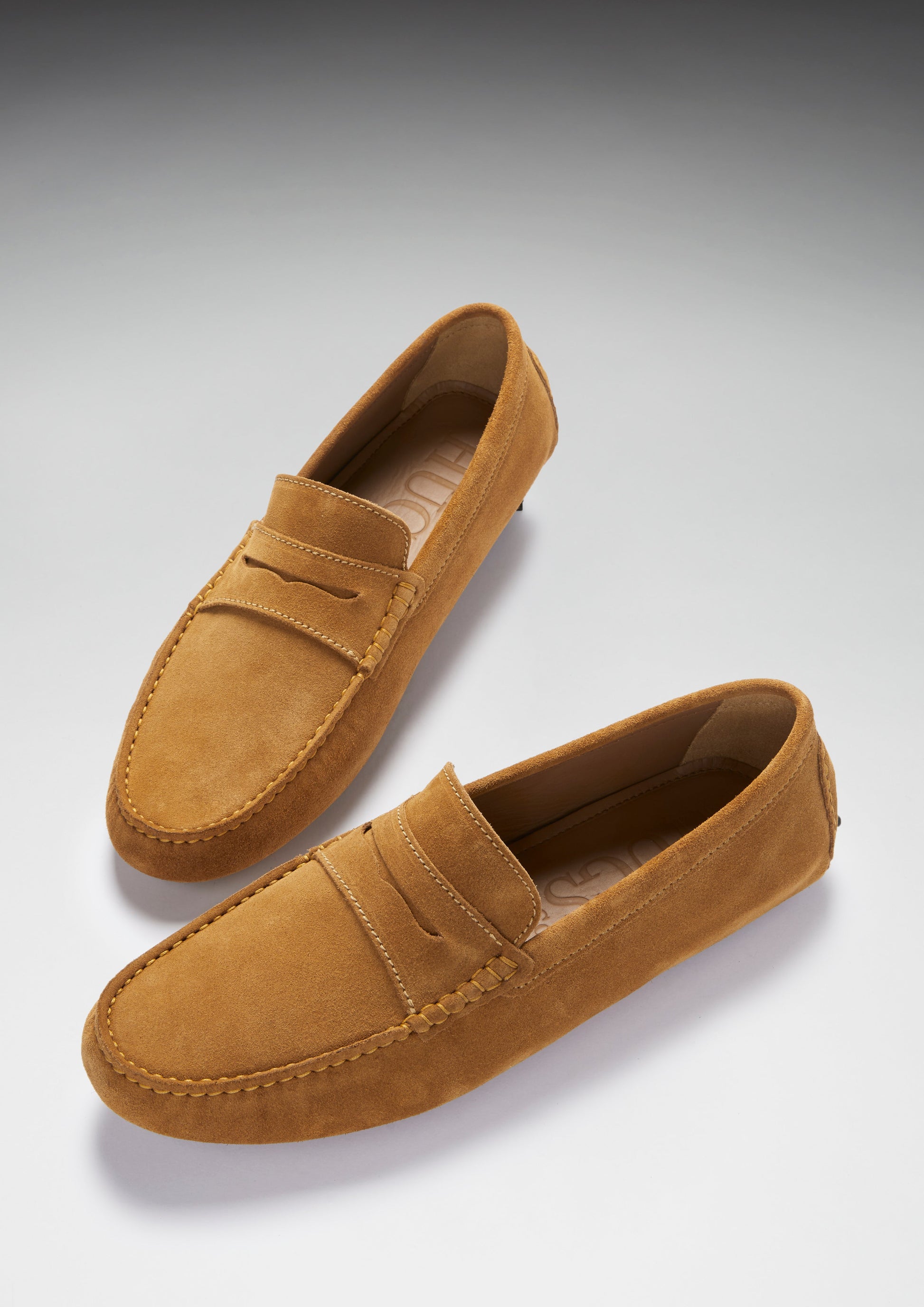 Pair of brown suede loafers on a light gray background