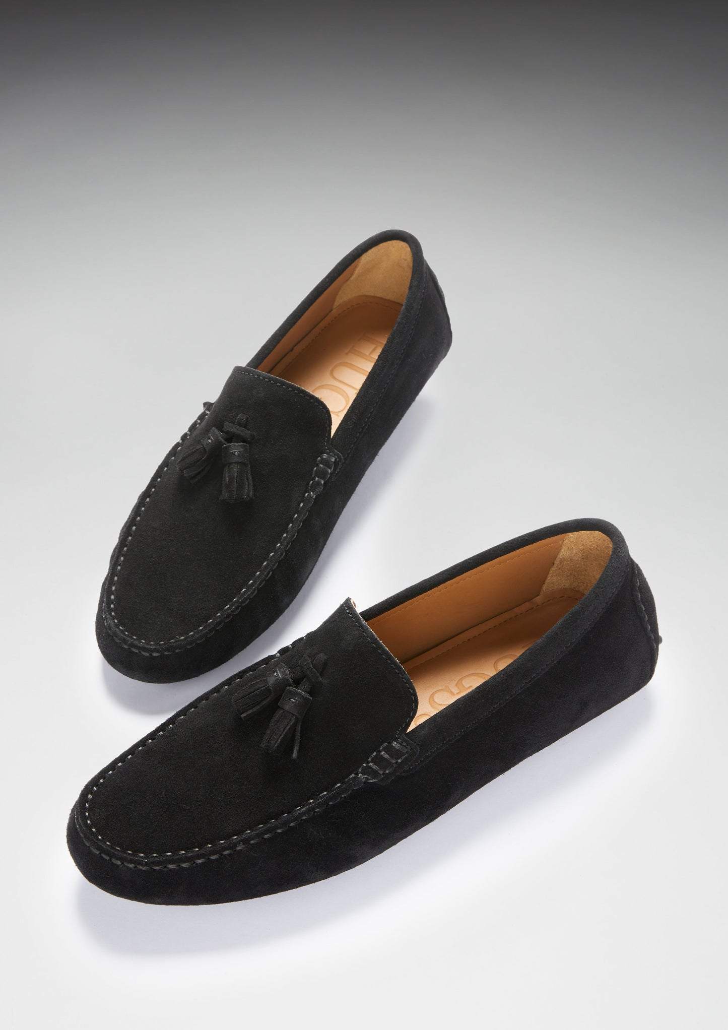 Pair of black suede loafers on a light gray background