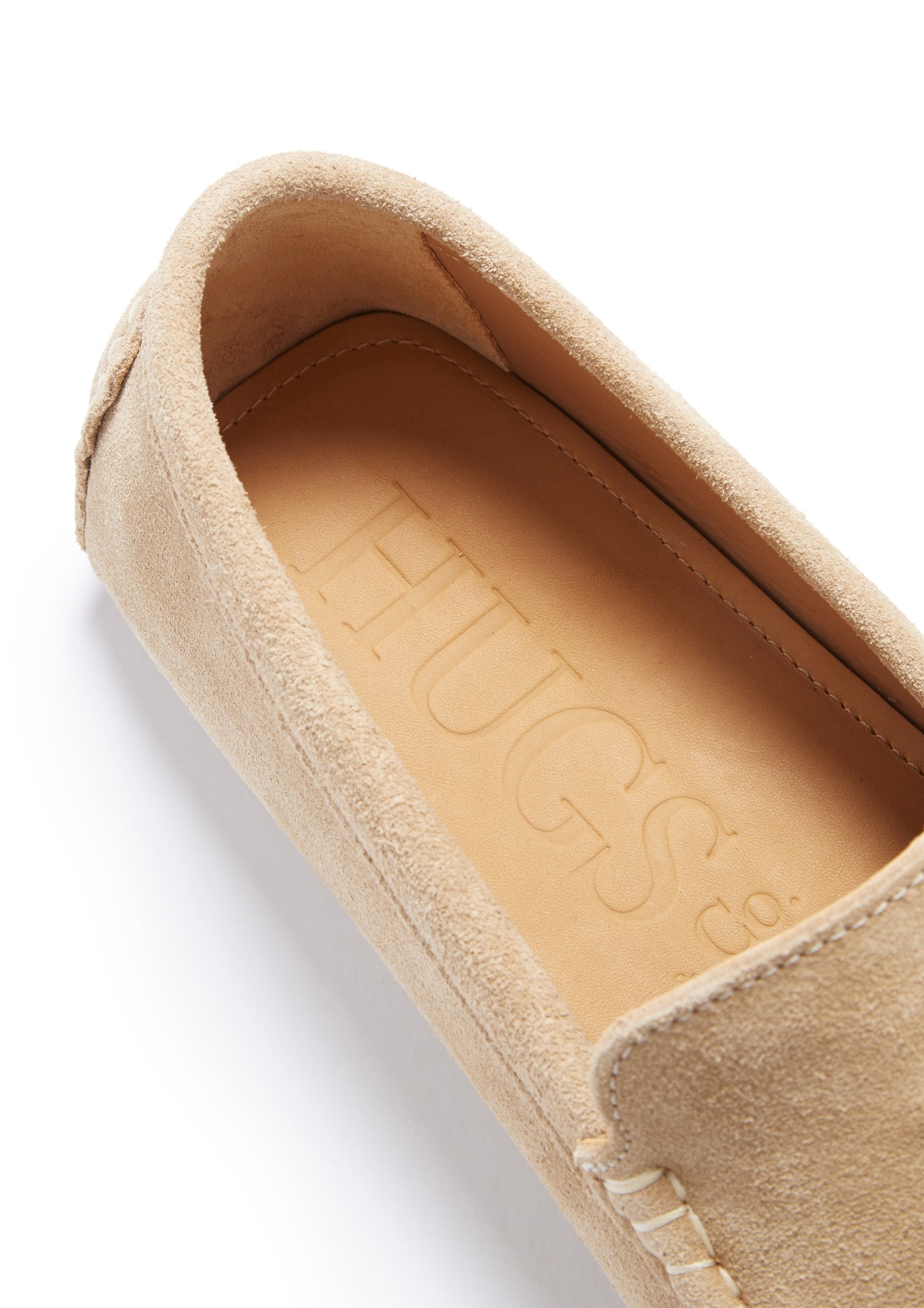 Beige slip-on shoe with 'Hugs' branding on a white background