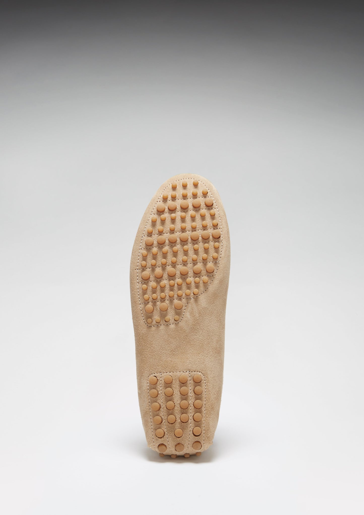 Close-up of a beige shoe sole with tread pattern on a light gray background