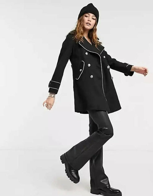 Person wearing a black coat with white buttons on a white background