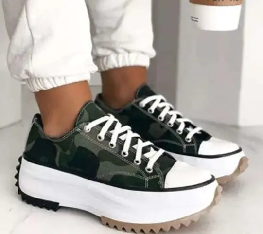 Green and black sneakers with white laces worn by a person on a light background