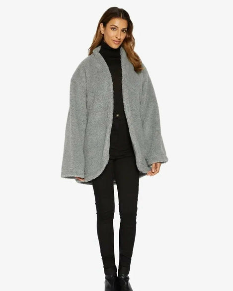 Woman wearing a gray coat over a black turtleneck and pants on a white background