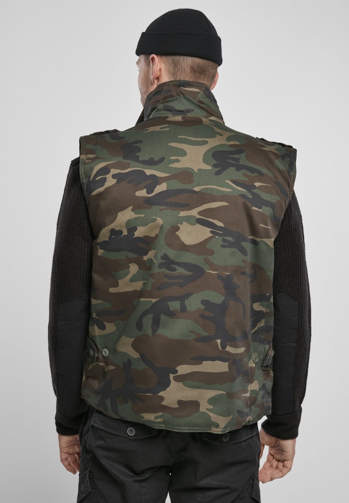 Person wearing a camouflage vest on a plain background