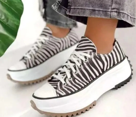 Zebra-striped sneakers worn with gray pants on a light background