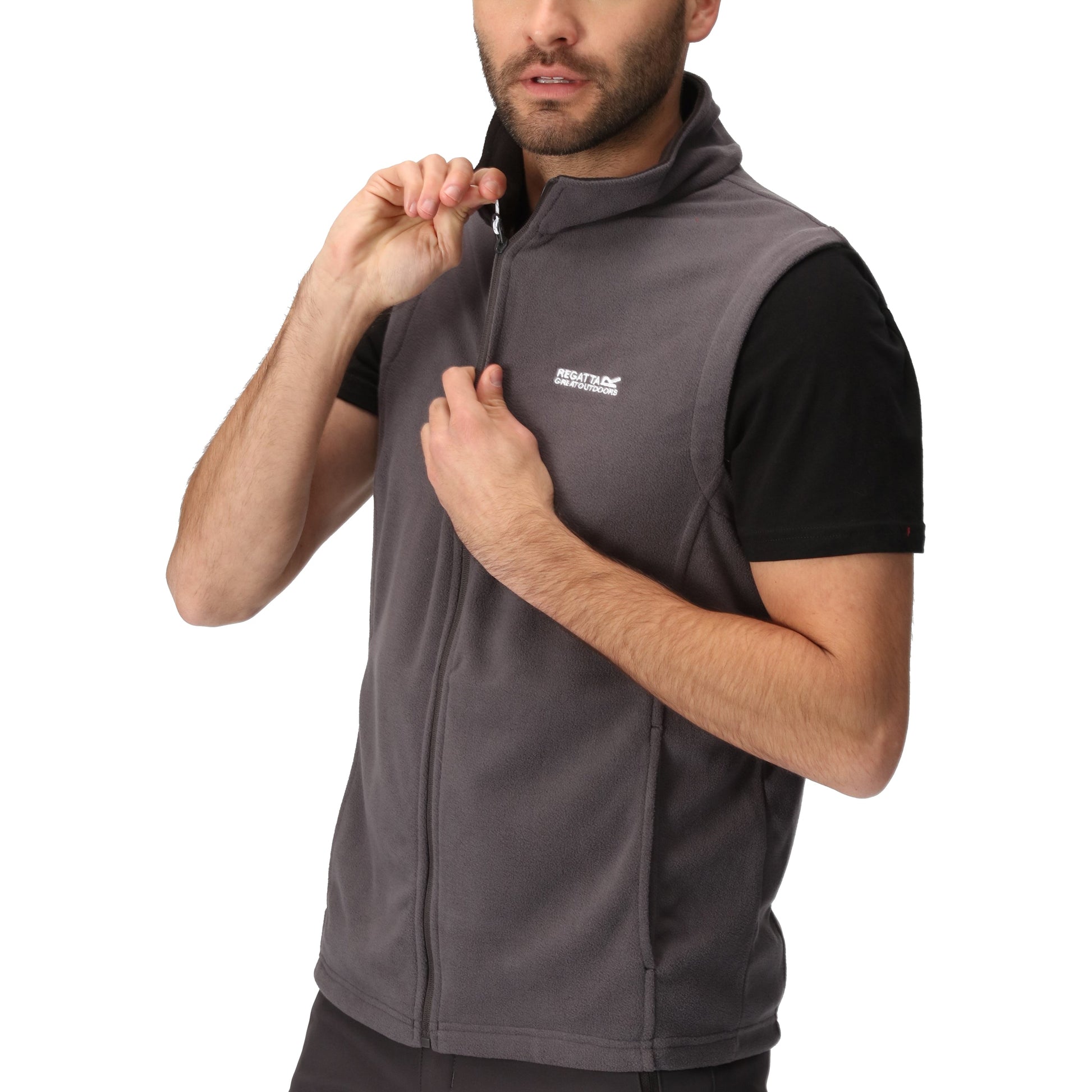 Man wearing a gray vest over a black shirt on a white background