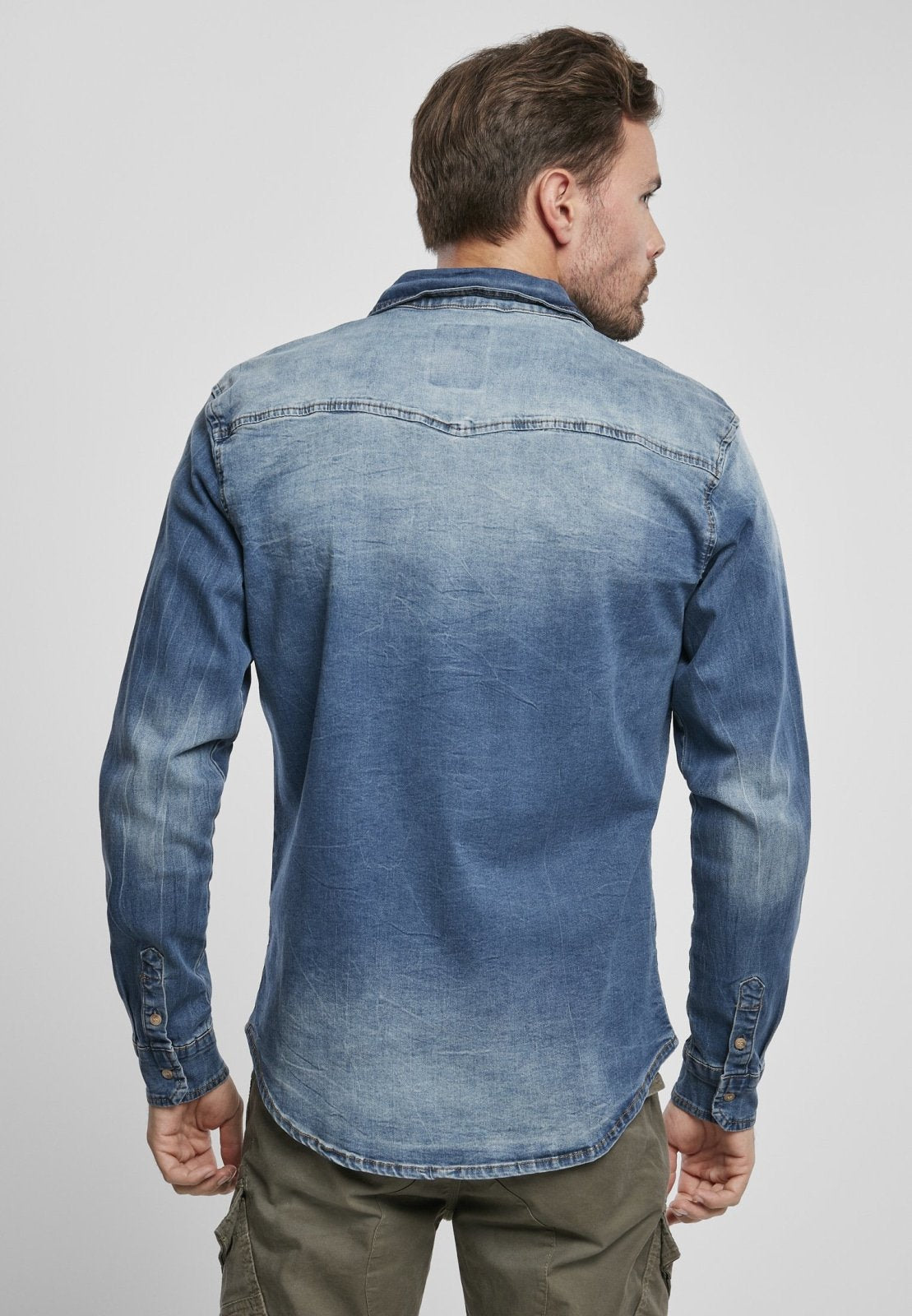 Man wearing a blue denim shirt on a plain background